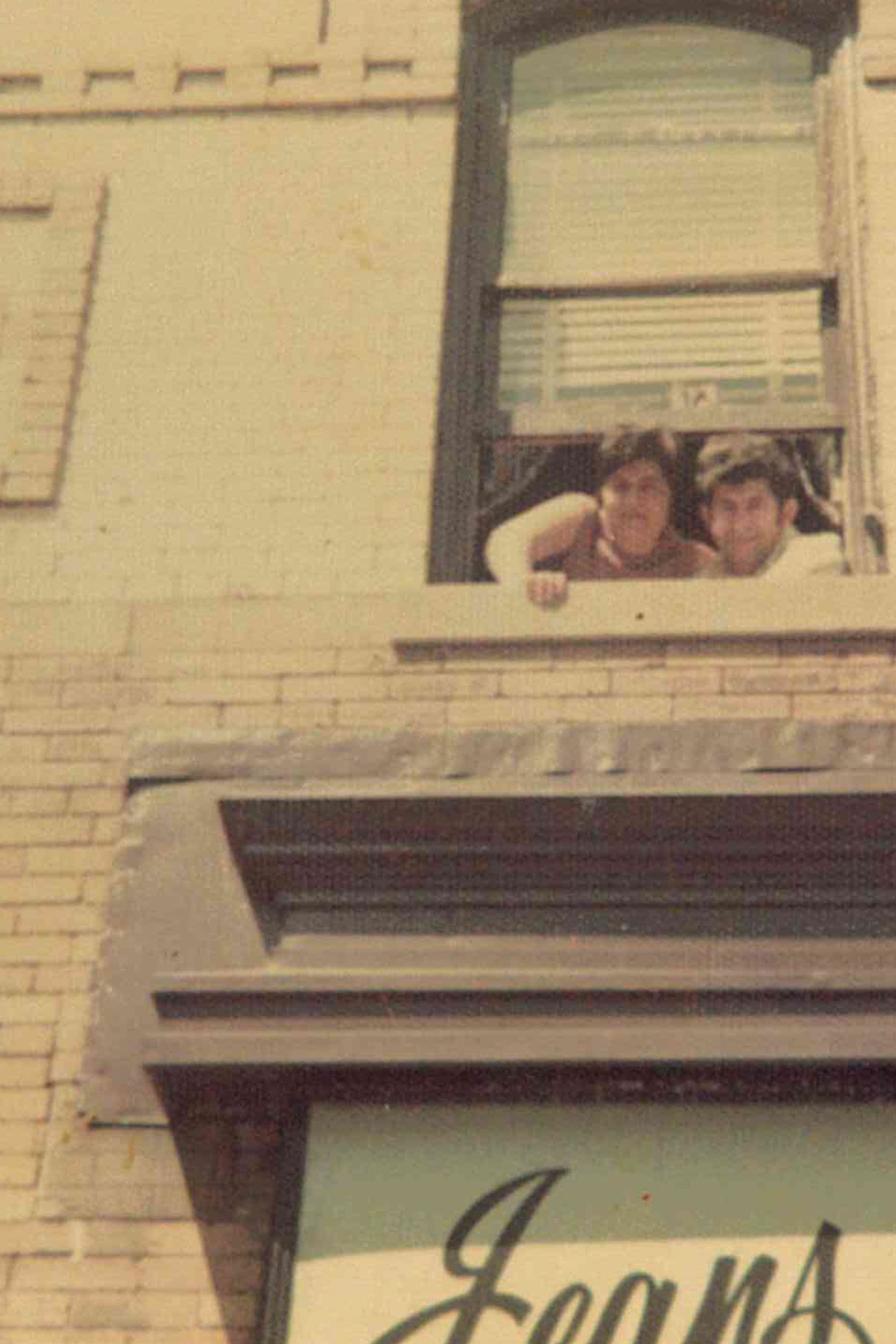 Man and woman looking down out of a window