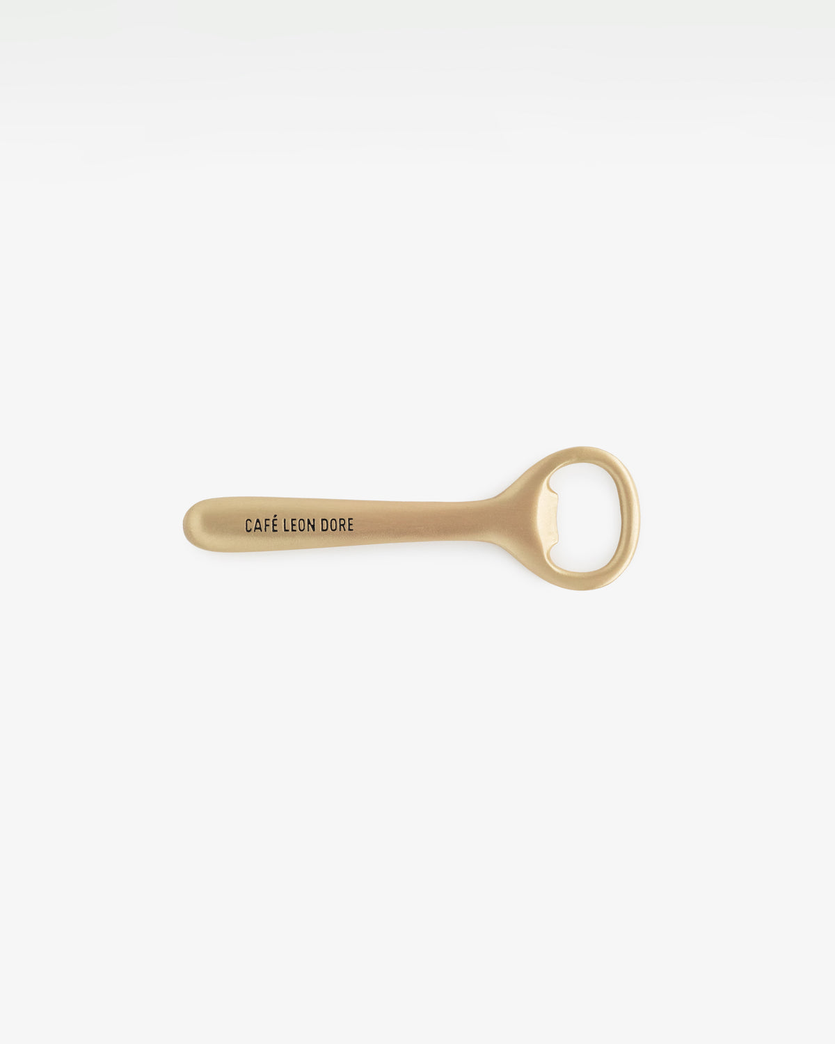 Café Leon Dore Bottle Opener in gold metal, featuring brand text, shown on a plain white background.