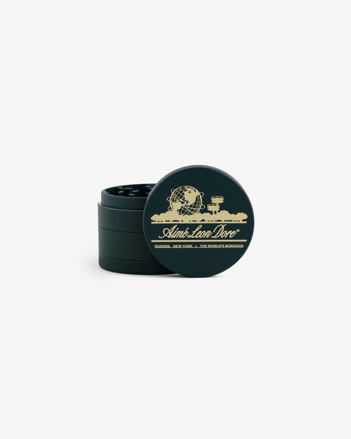 Large Unisphere Herb Grinder in dark green with gold Queens, NY skyline and Aimé Leon Dore logo on the lid, slightly open.