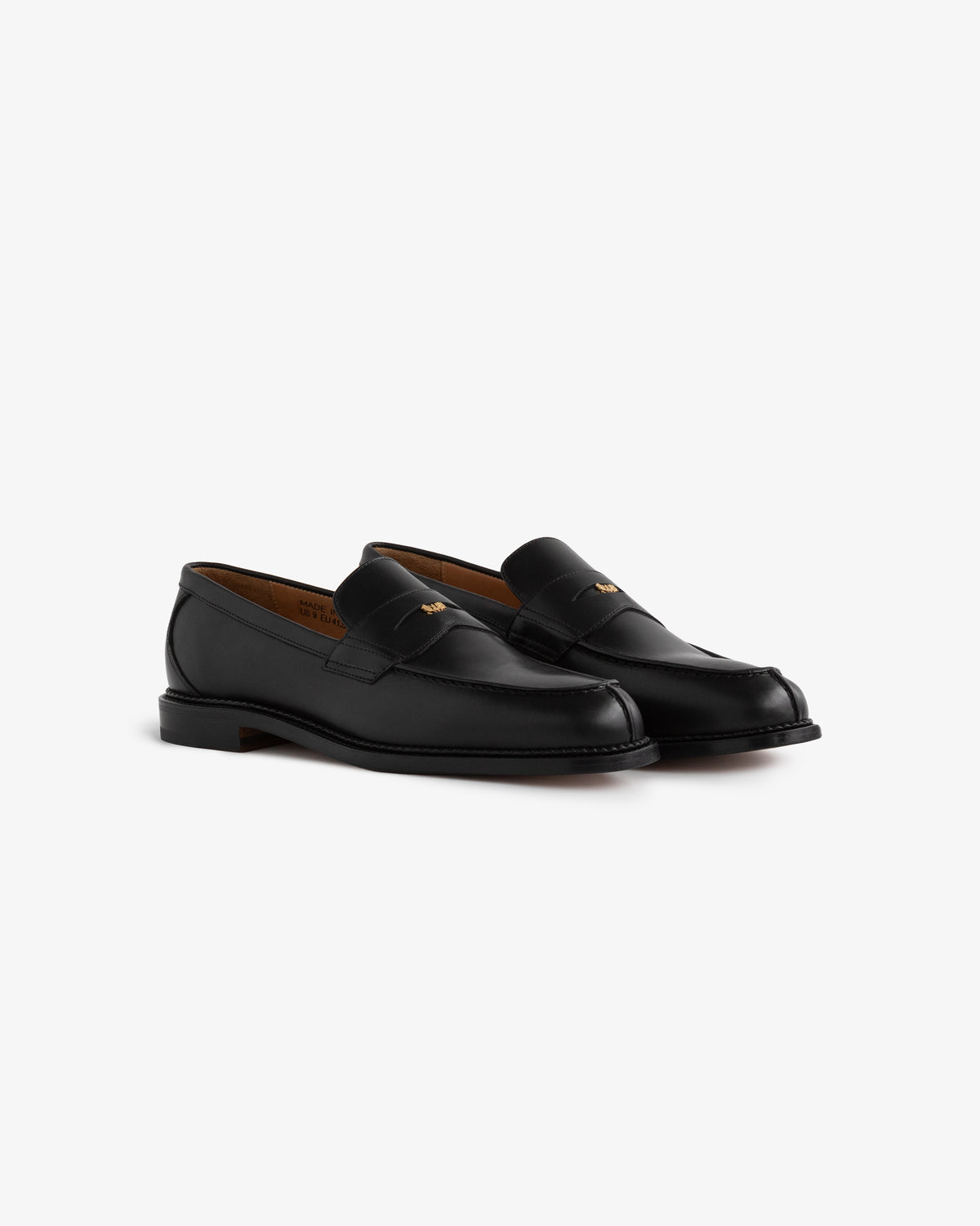 Queens Crest Loafer: black leather loafers with a gold emblem on the upper, shown on a white background.