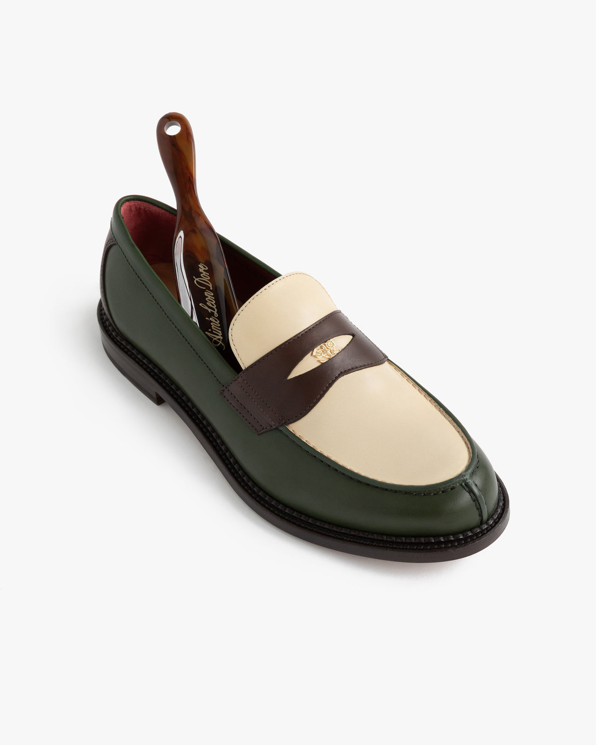 Queens Crest Loafer in green, cream, and brown leather with a shoehorn inside on a white background.