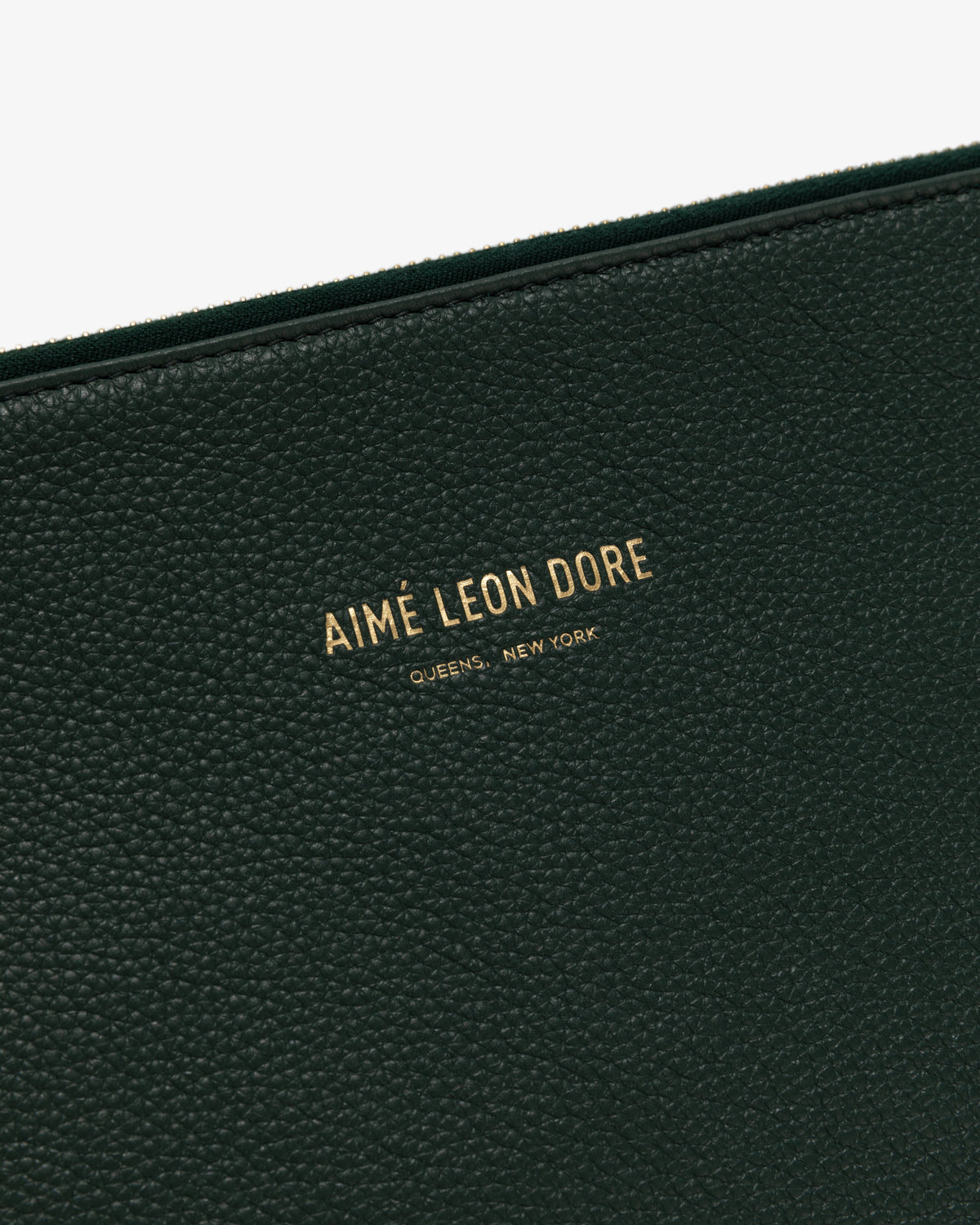 Close-up of the Medium Leather Pouch in textured green leather with AIMÉ LEON DORE QUEENS, NEW YORK embossed in gold.