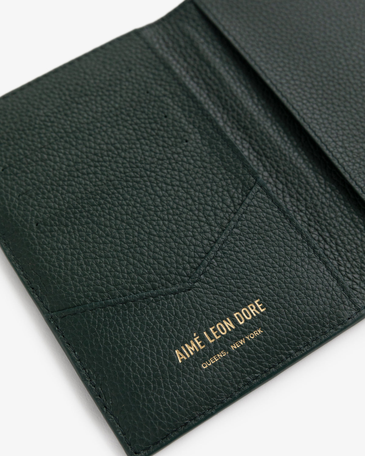 Dark green Leather Passport Holder with AIMÉ LEON DORE QUEENS, NEW YORK embossed in gold inside.