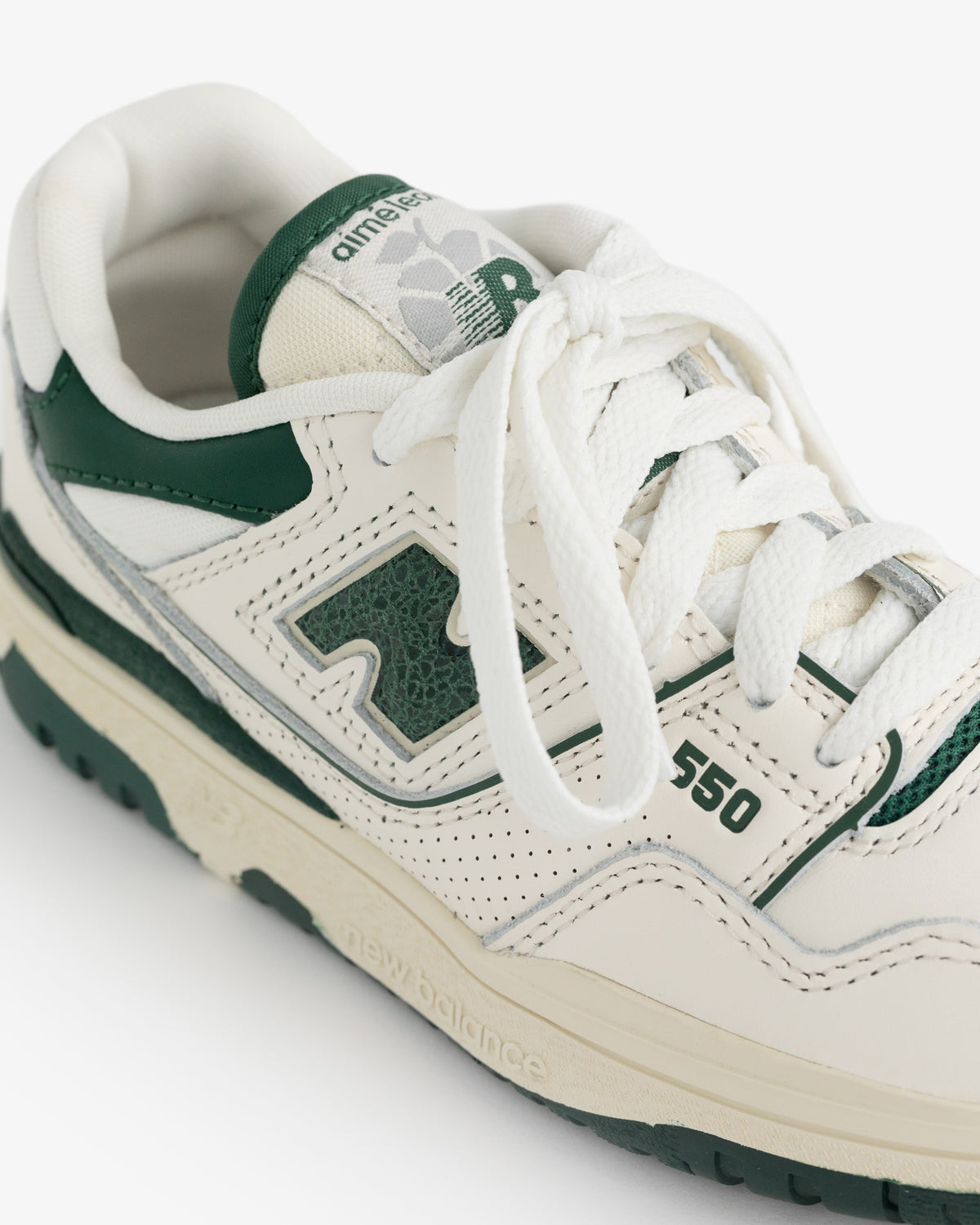 Close-up of ALD / NB P550 Basketball Oxfords for little kids in white and dark green with laces and perforated leather.