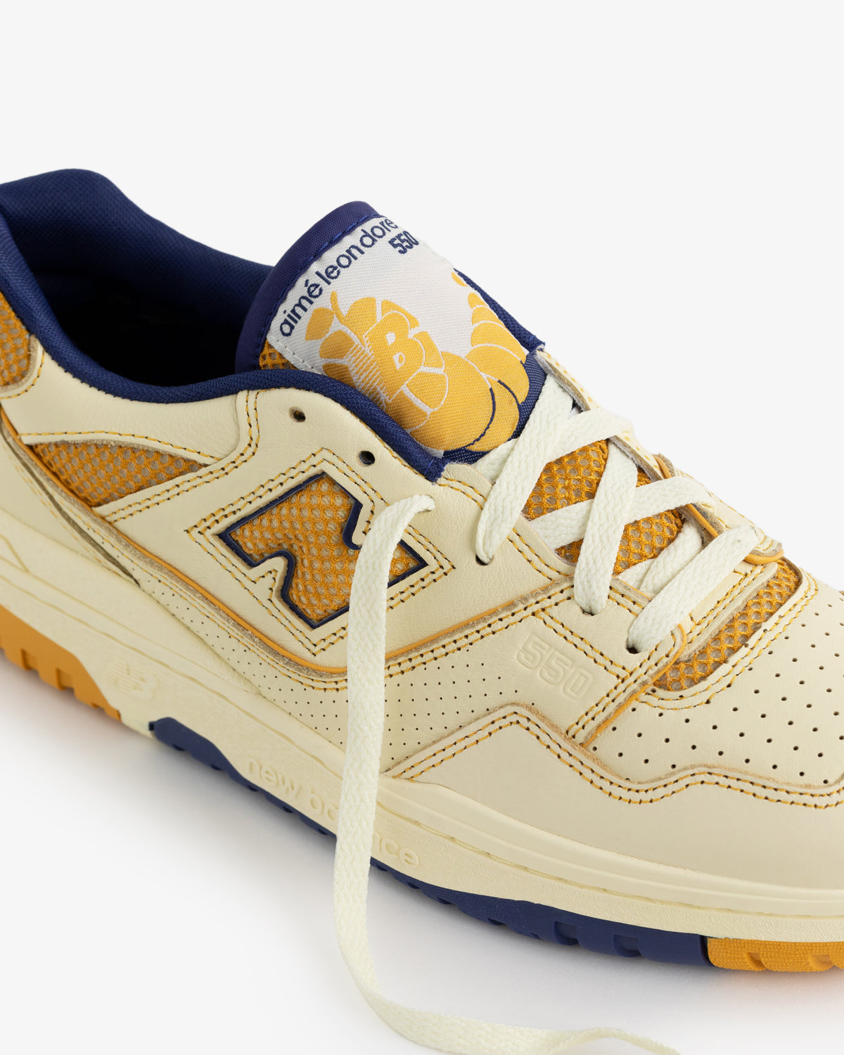 Cream and yellow ALD/NB P550 Basketball Oxfords with blue accents and a cartoon bee on the tongue.