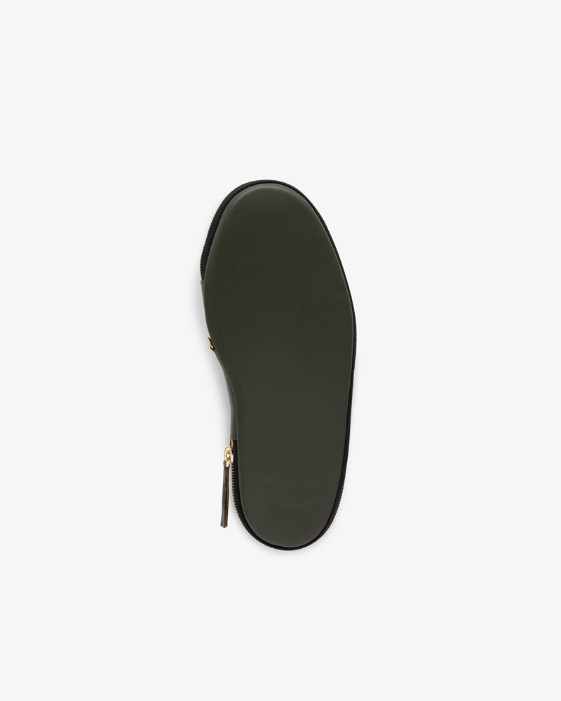 The Leather Travel Slipper has a green sole with a gold zipper detail, shown from the bottom on a white background.