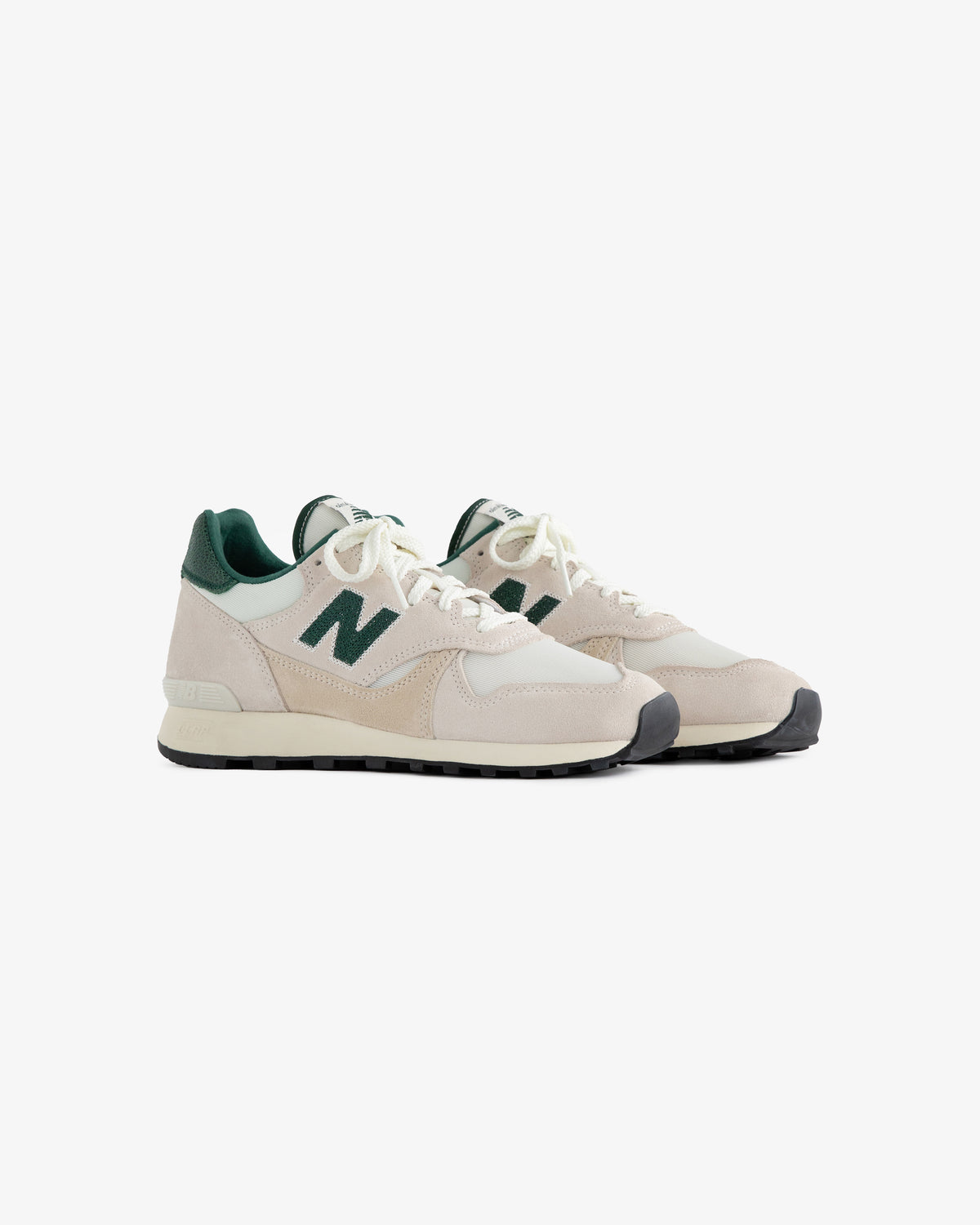 A pair of ALD / New Balance 475 beige sneakers with green accents and a green N logo on a white background.