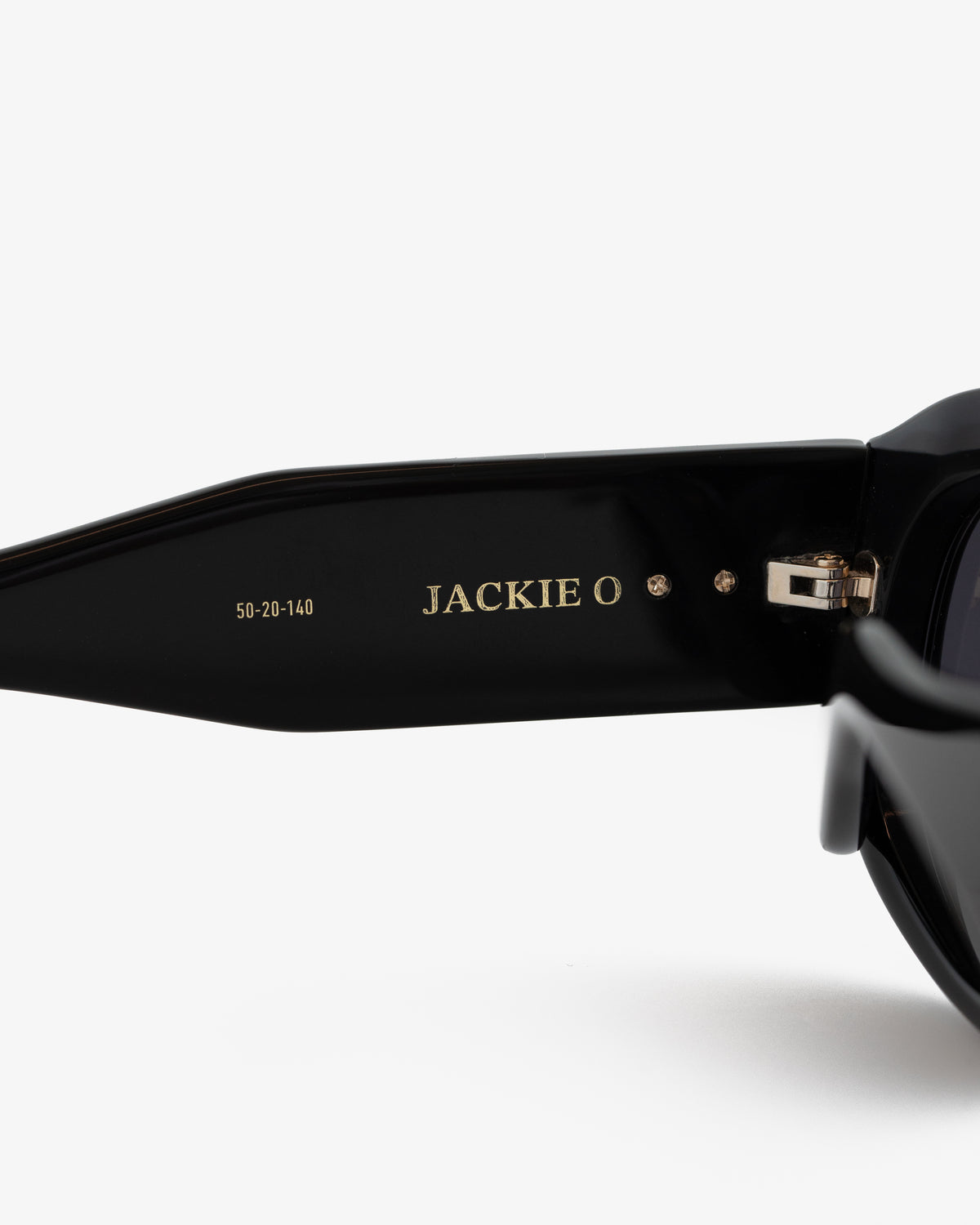 Close-up of Jackie O Sunglasses' black arm with product name and size numbers engraved in gold inside.