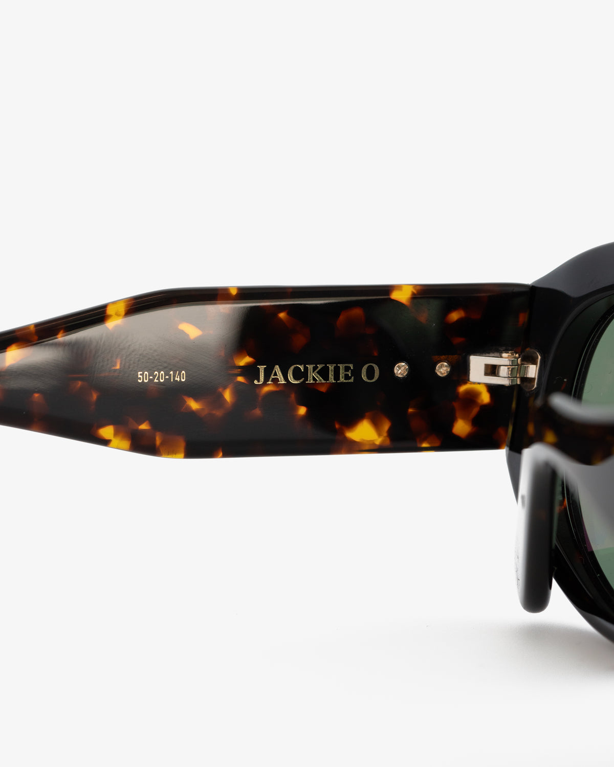 Close-up of Jackie O Sunglasses arm with product name and size details engraved in gold lettering.