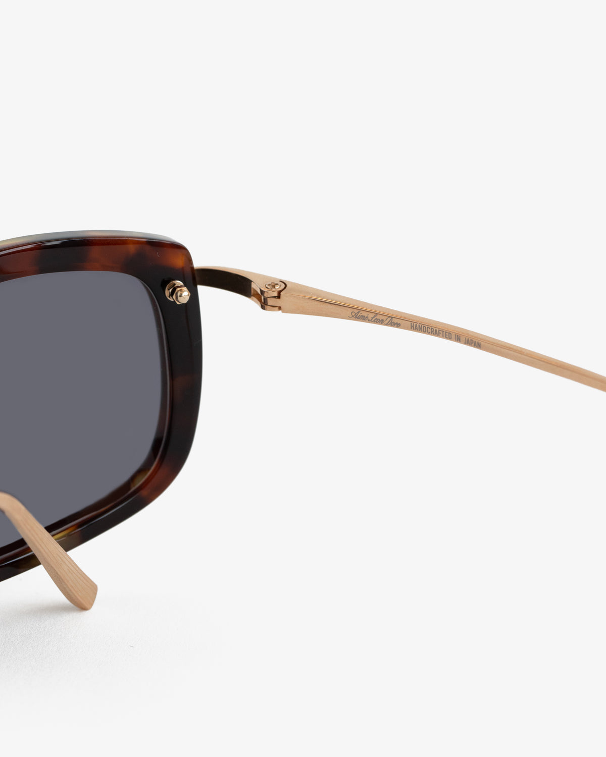 Close-up of Ace Sunglasses with tortoiseshell frames, gold metal arms, and dark lenses on a white background.