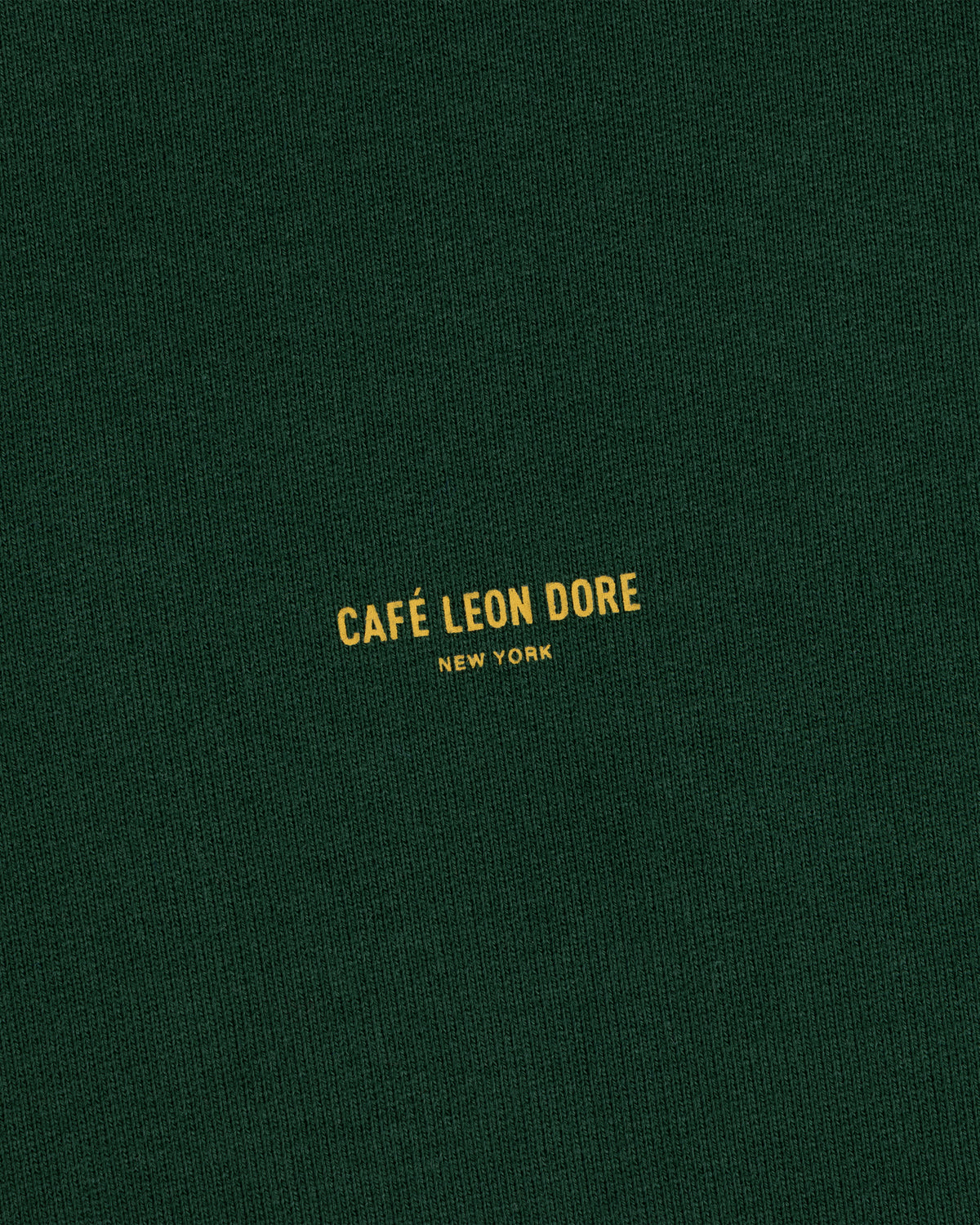 Dark green Café Leon Dore Crewneck Sweatshirt with centered yellow “CAFÉ LEON DORE NEW YORK” text.