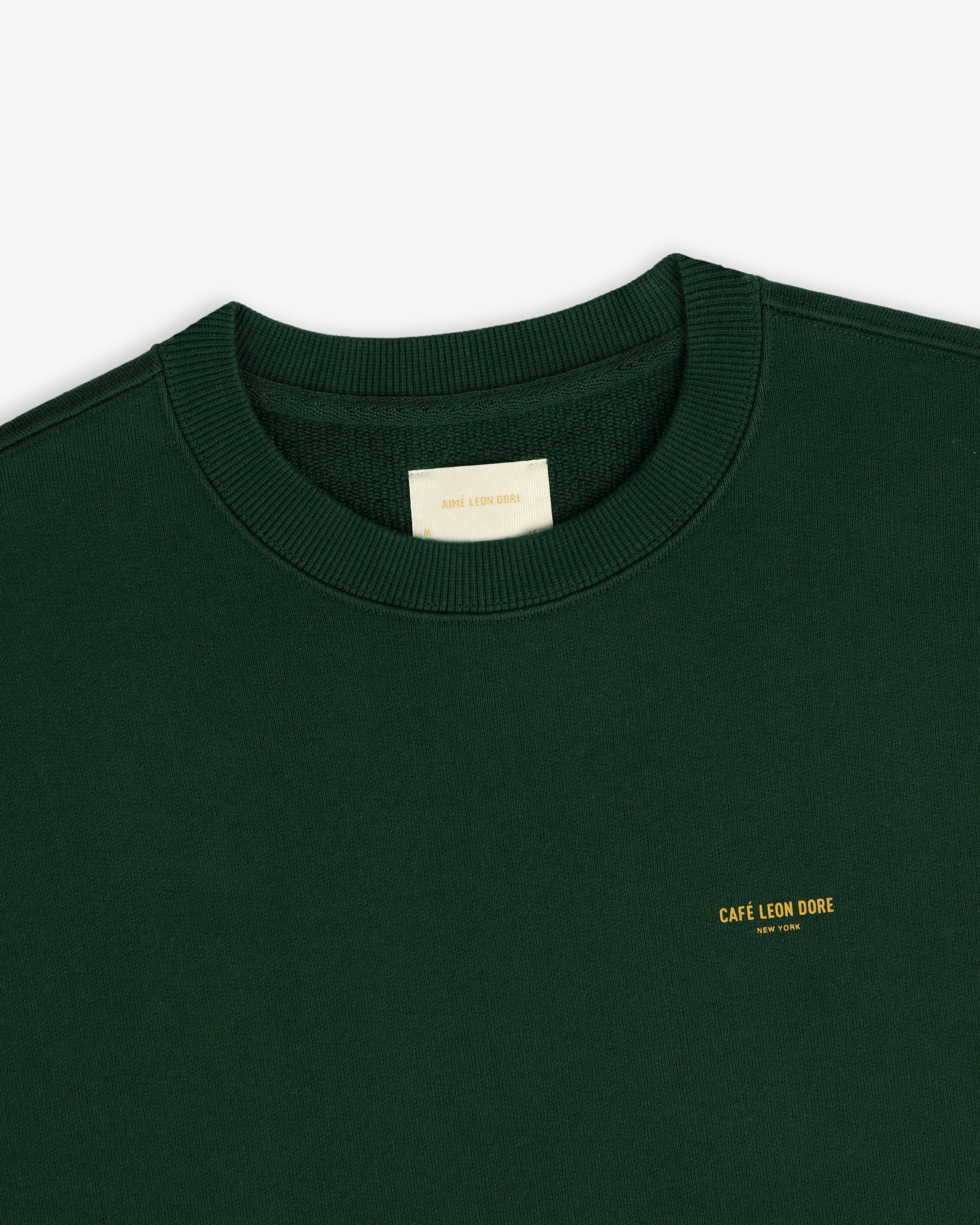 Forest green Café Leon Dore Crewneck with small yellow CAFÉ LEON DORE text on the chest.