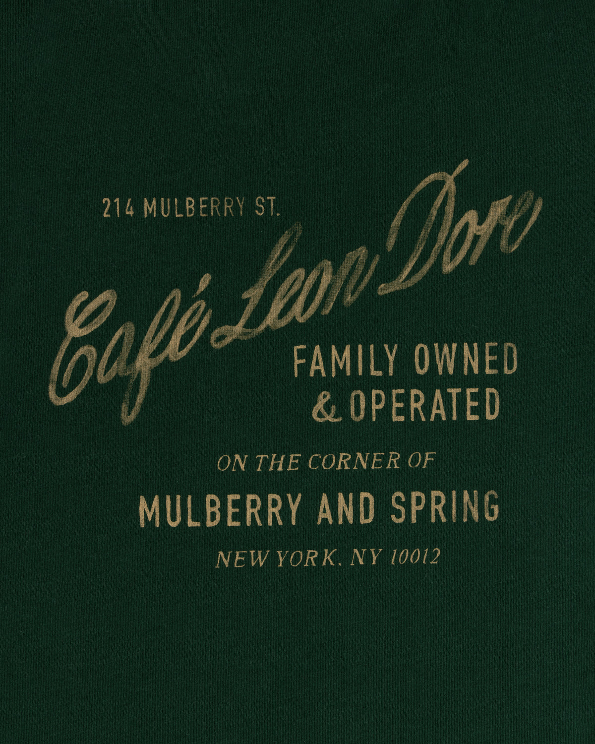 Text on dark green reads: Café Leon Dore Mulberry Tee, family owned, 214 Mulberry St, New York, NY 10012.