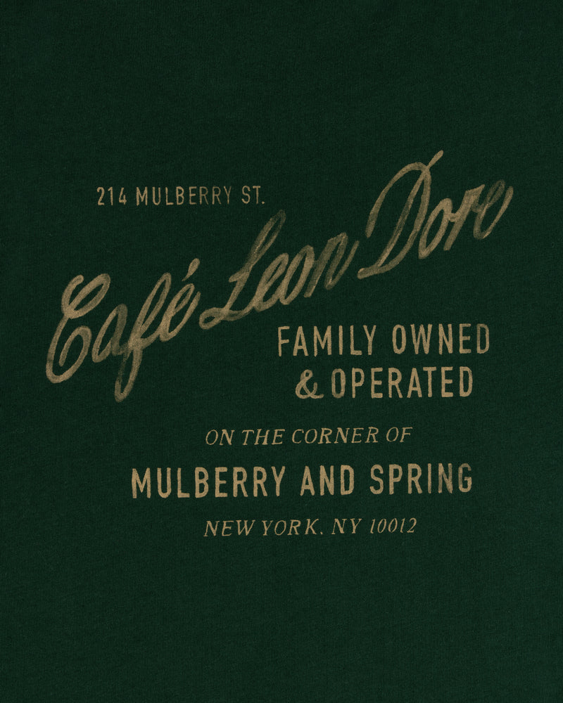 Text on dark green reads: Café Leon Dore Mulberry Tee, family owned, 214 Mulberry St, New York, NY 10012.