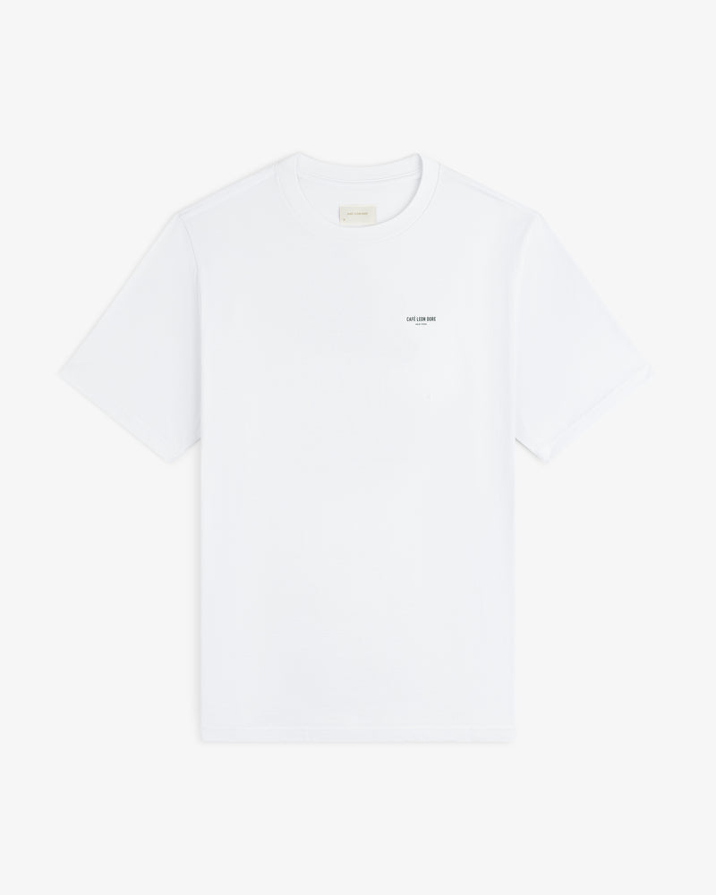 Café Leon Dore Caricature Tee: white short-sleeve shirt with small black text on left chest, on white background.
