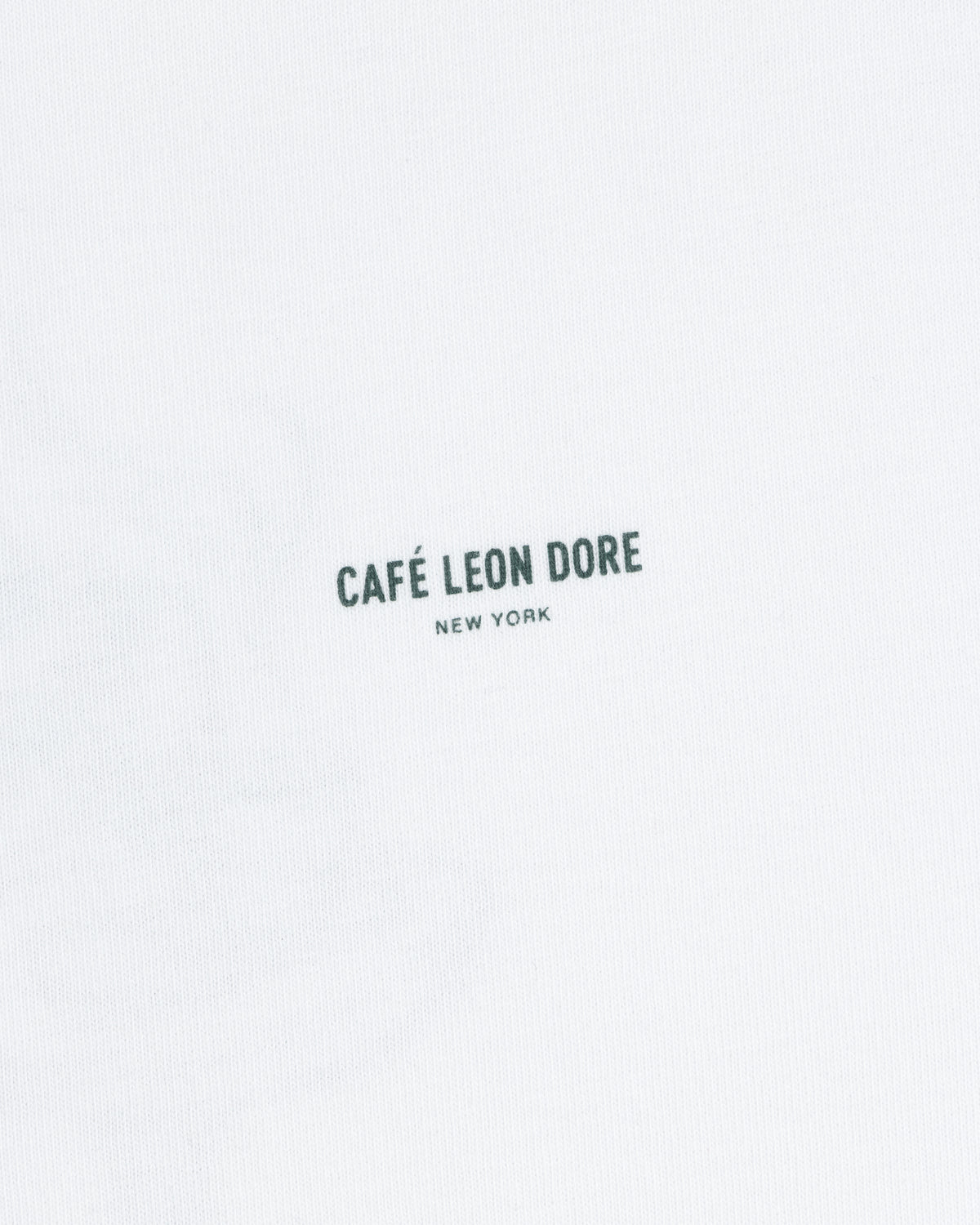 White Café Leon Dore Caricature Tee with “CAFÉ LEON DORE NEW YORK” in small black letters near the center.