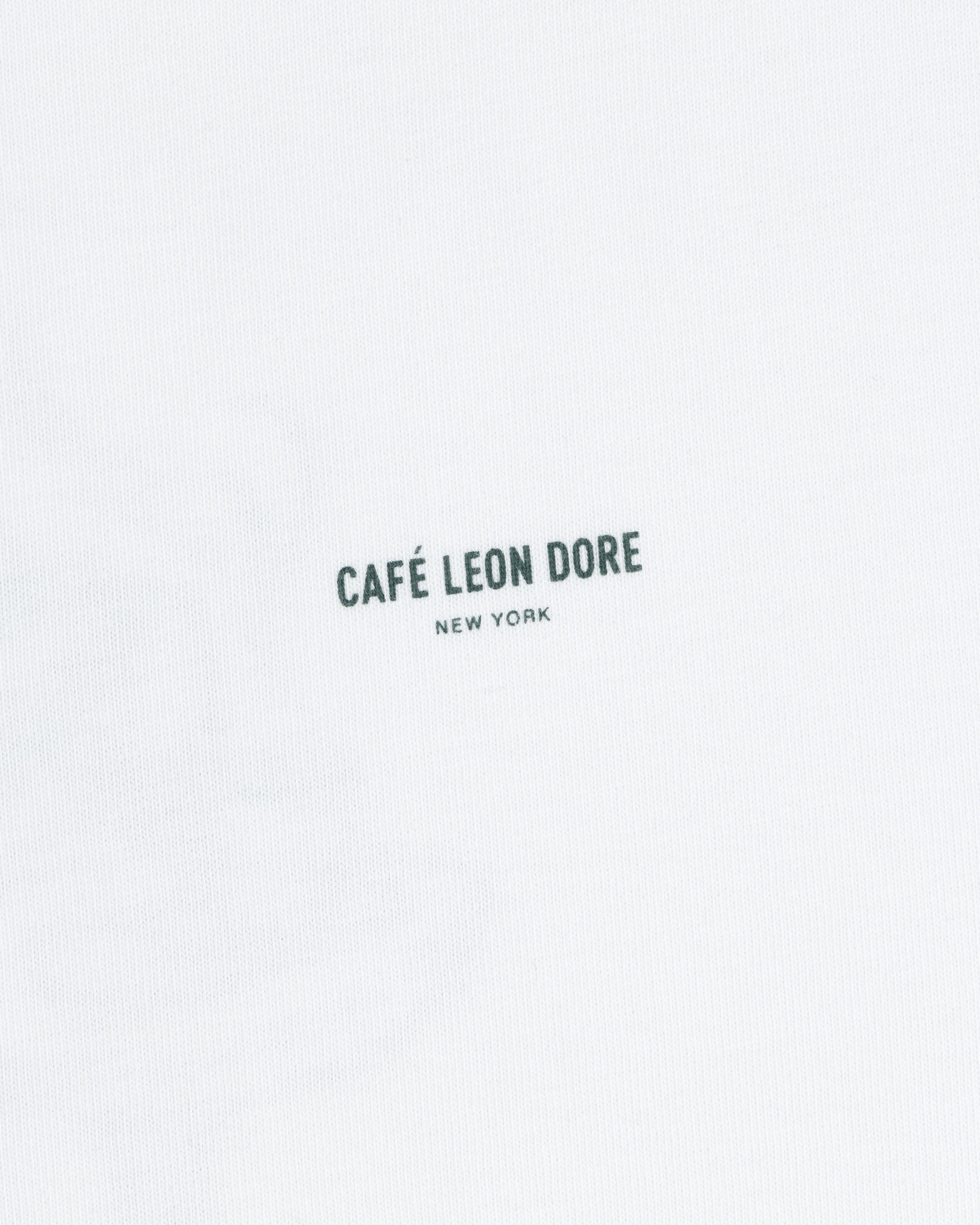 White Café Leon Dore Caricature Tee with “CAFÉ LEON DORE NEW YORK” in small black letters near the center.
