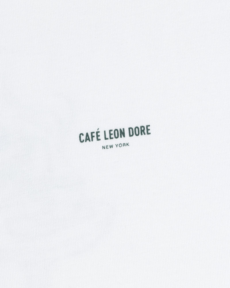 White Café Leon Dore Caricature Tee with “CAFÉ LEON DORE NEW YORK” in small black letters near the center.