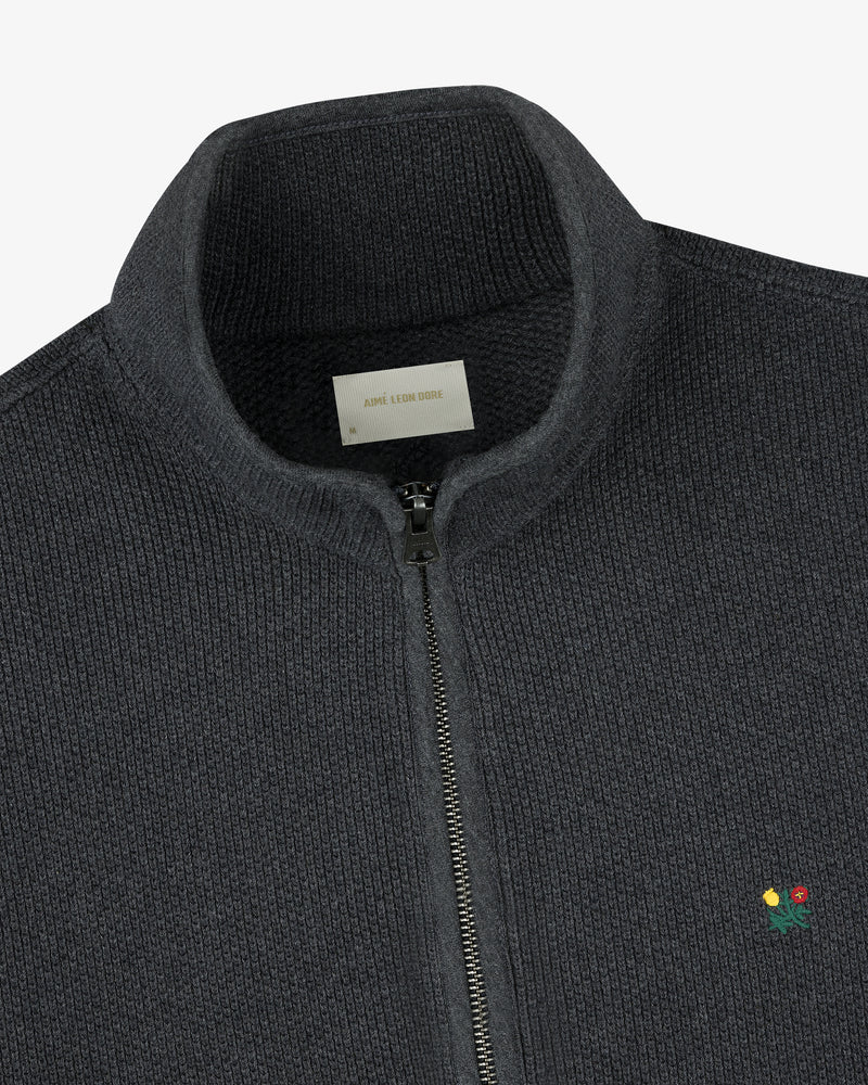 Crest Piqué Half-Zip Pullover in dark gray with a small embroidered flower detail, shown from the collar down.