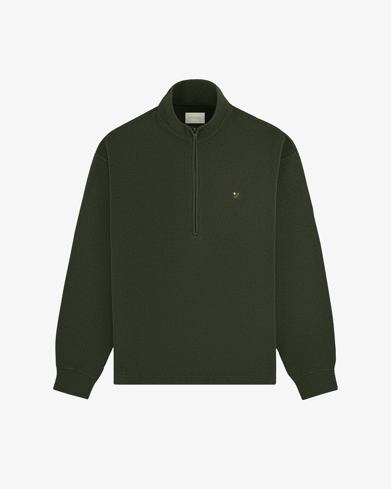 Crest Piqué Half-Zip Pullover in dark green with ribbed texture, small chest logo, and long sleeves on white background.