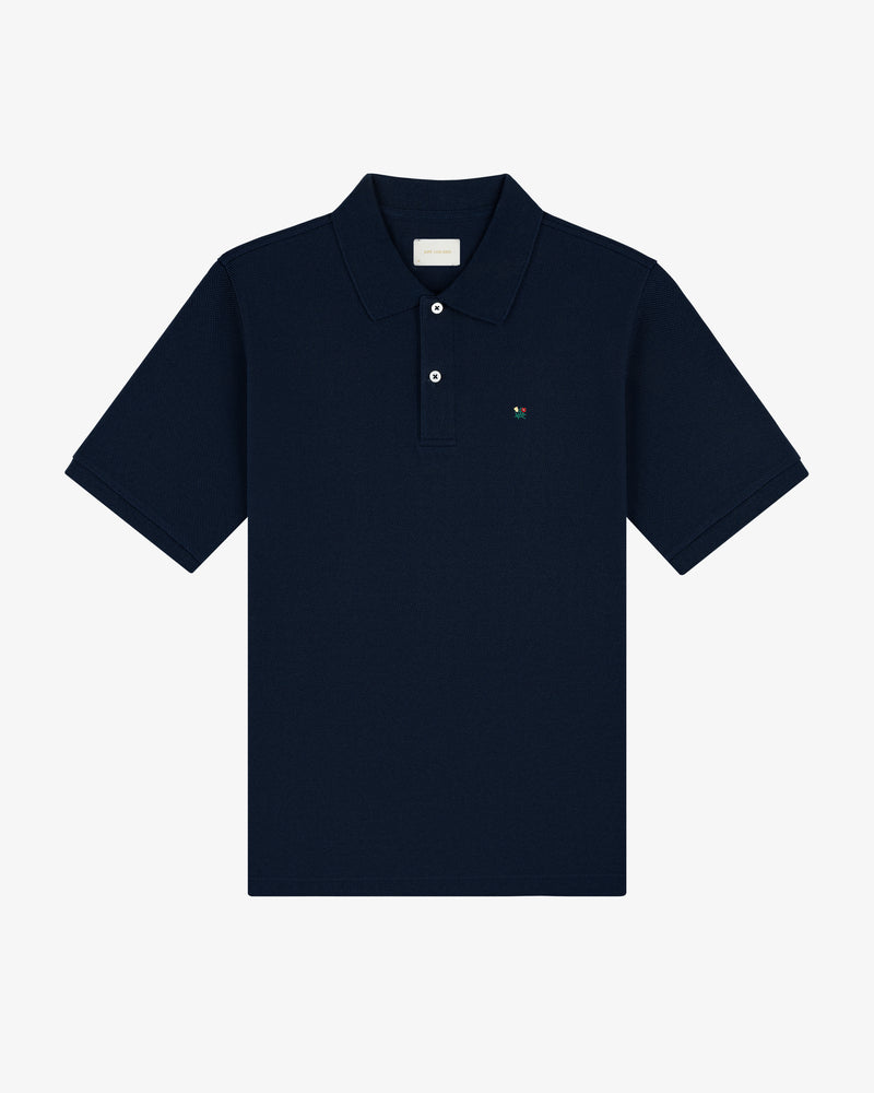 Crest Piqué Polo in navy blue featuring short sleeves, a collar, button placket, and small chest logo on white background.