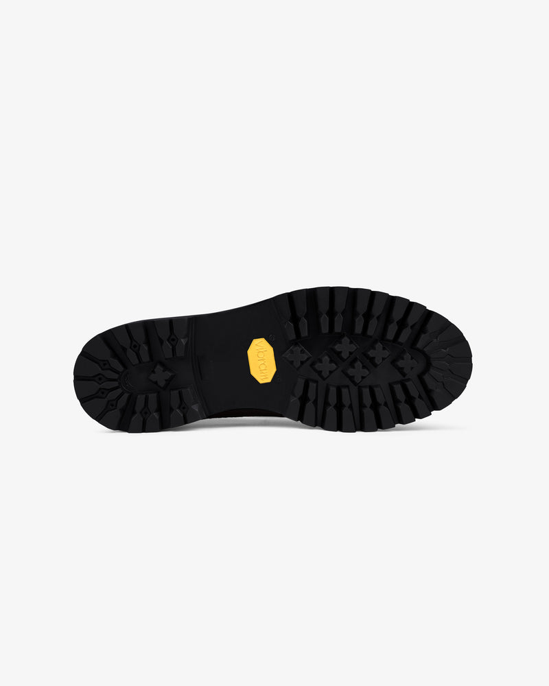 The Lug Sole Queens Crest Loafer features a black lugged sole with a yellow hexagonal Vibram logo on a white background.