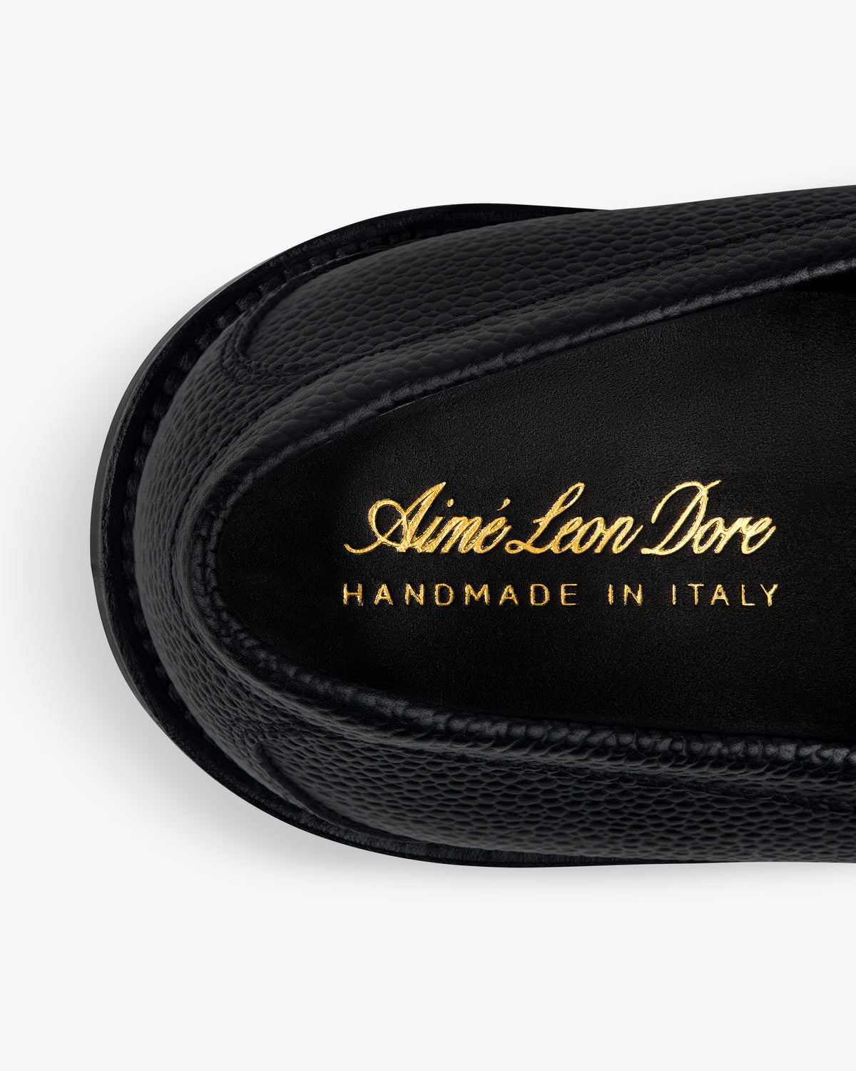 Close-up of a black Lug Sole Queens Crest Loafer with Aimé Leon Dore HANDMADE IN ITALY printed in gold on the insole.