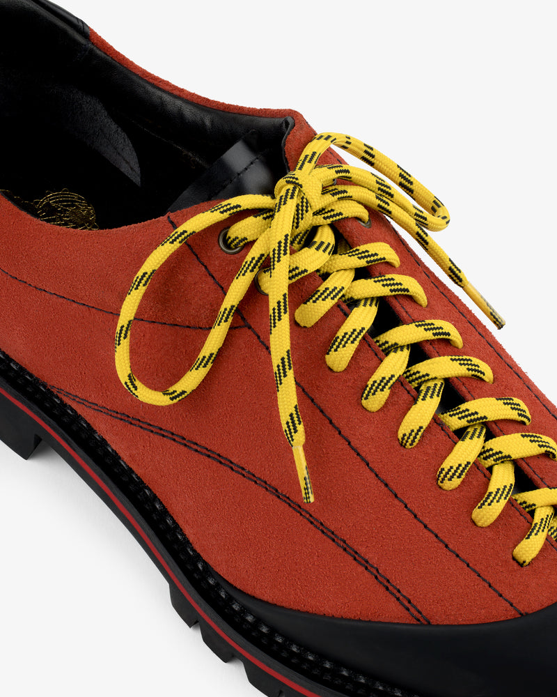 Close-up of the Suede Derby Hiker in red suede with yellow and black striped laces and a black sole.