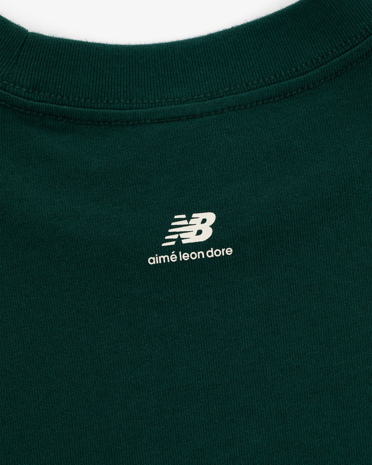 Close-up of the ALD / New Balance SONNY NY Long-Sleeve Tee in green with white logos near the neckline.