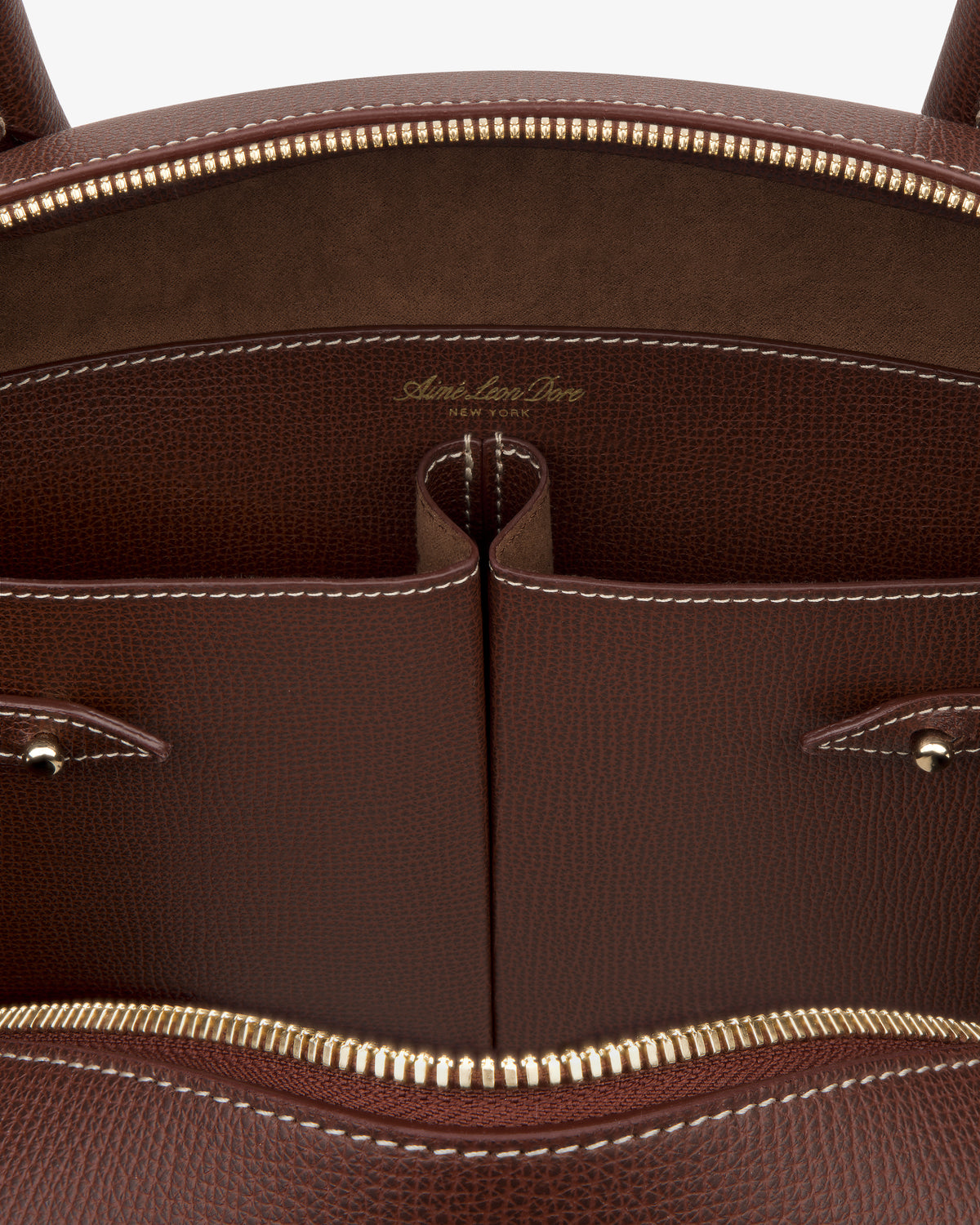 Close-up of the Full Grain Leather Crescent Shoulder Bag's brown interior with gold zippers and white stitching.