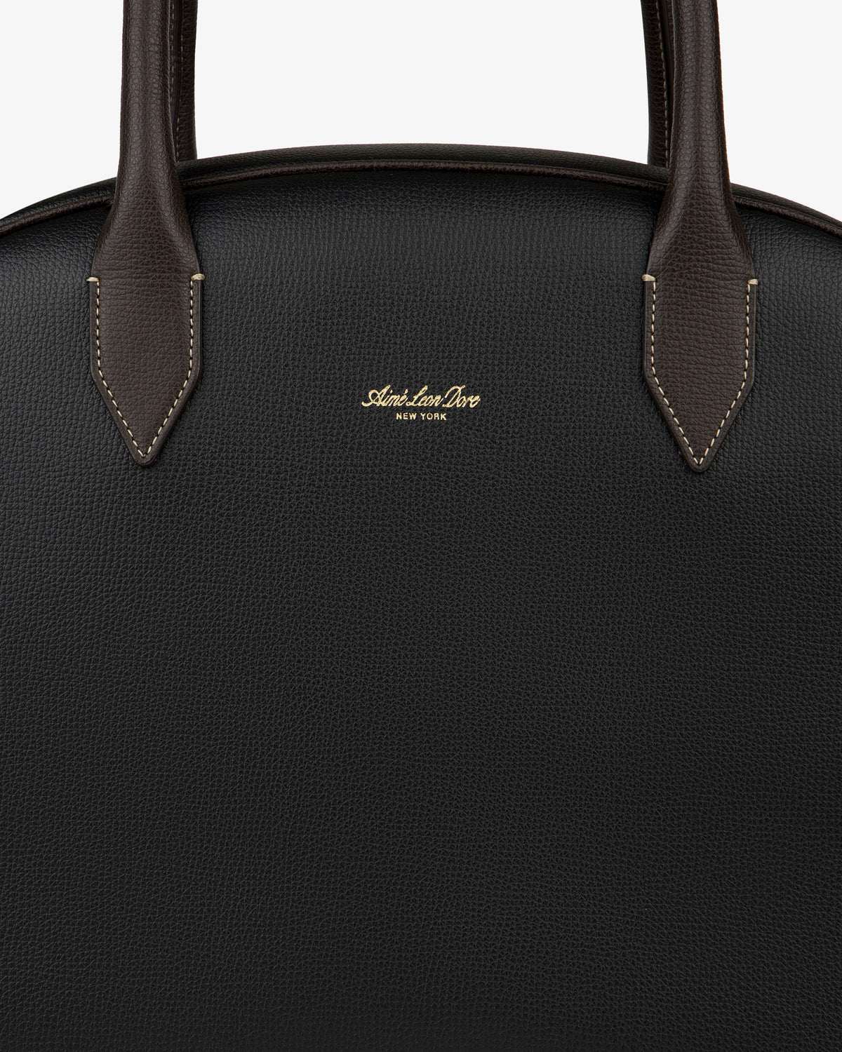 Close-up of the Full Grain Leather Crescent Shoulder Bag in black with brown handles and gold Sloan Ian Dove New York text.