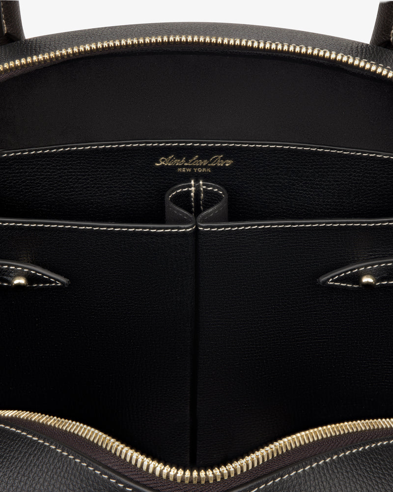 Close-up of Full Grain Leather Crescent Shoulder Bag’s open black interior with gold zipper, showing stitched pockets and logo.
