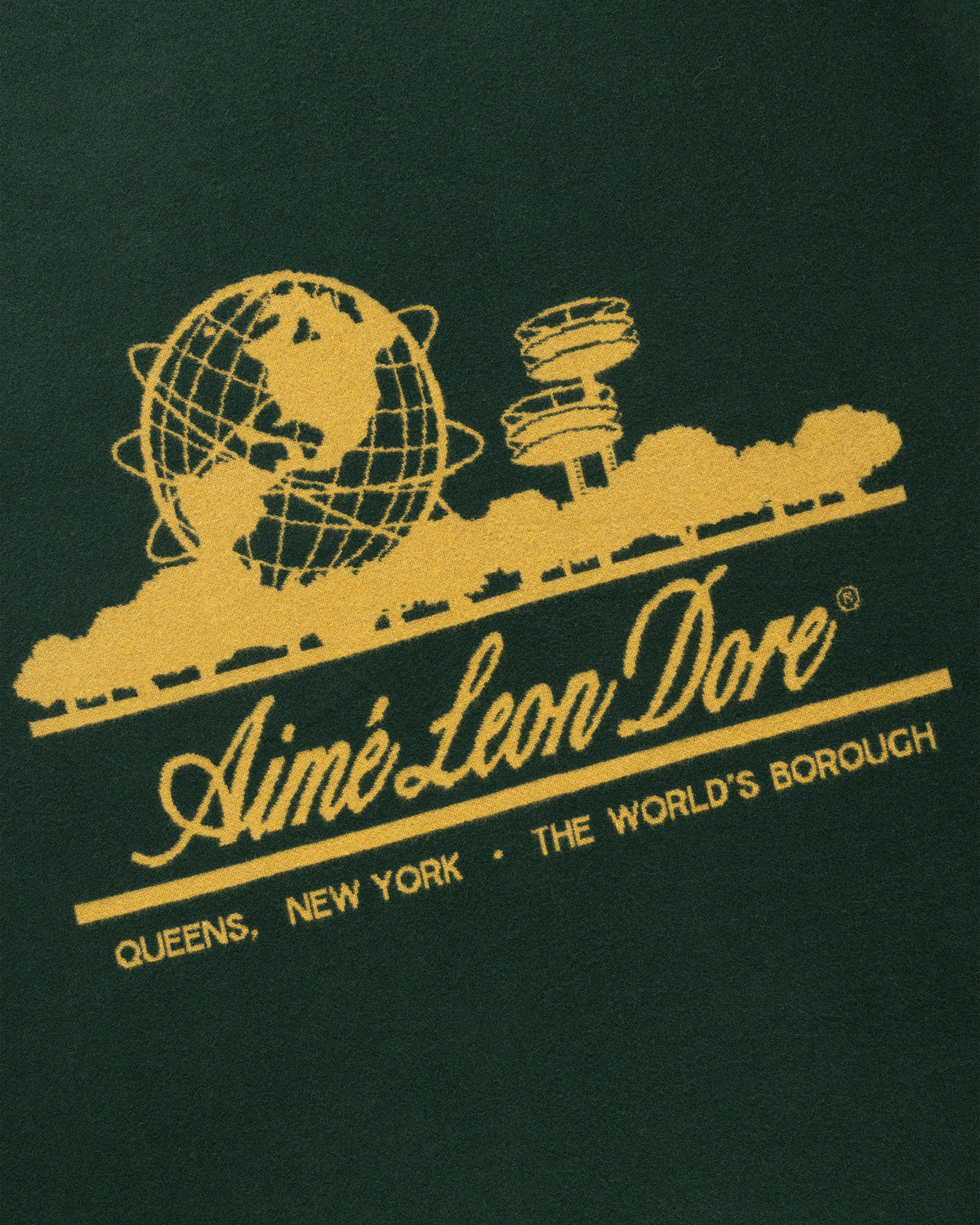 Gold graphic of globe, trees & towers above "Aimé Leon Dore, Queens, NY" on green Unisphere Wool Blanket.