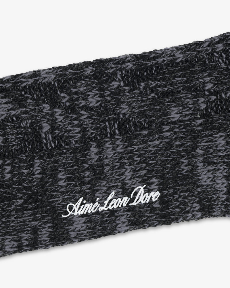 Close-up of a knitted black and gray Cable Knit Hiking Sock with Aimé Leon Dore embroidered in white script.