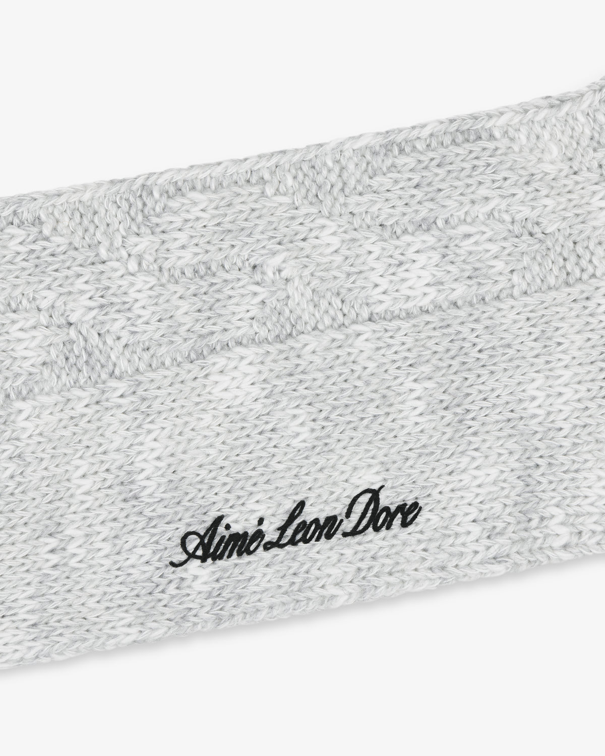 Close-up of a light gray Cable Knit Hiking Sock with Aimé Leon Dore embroidered in black cursive text.