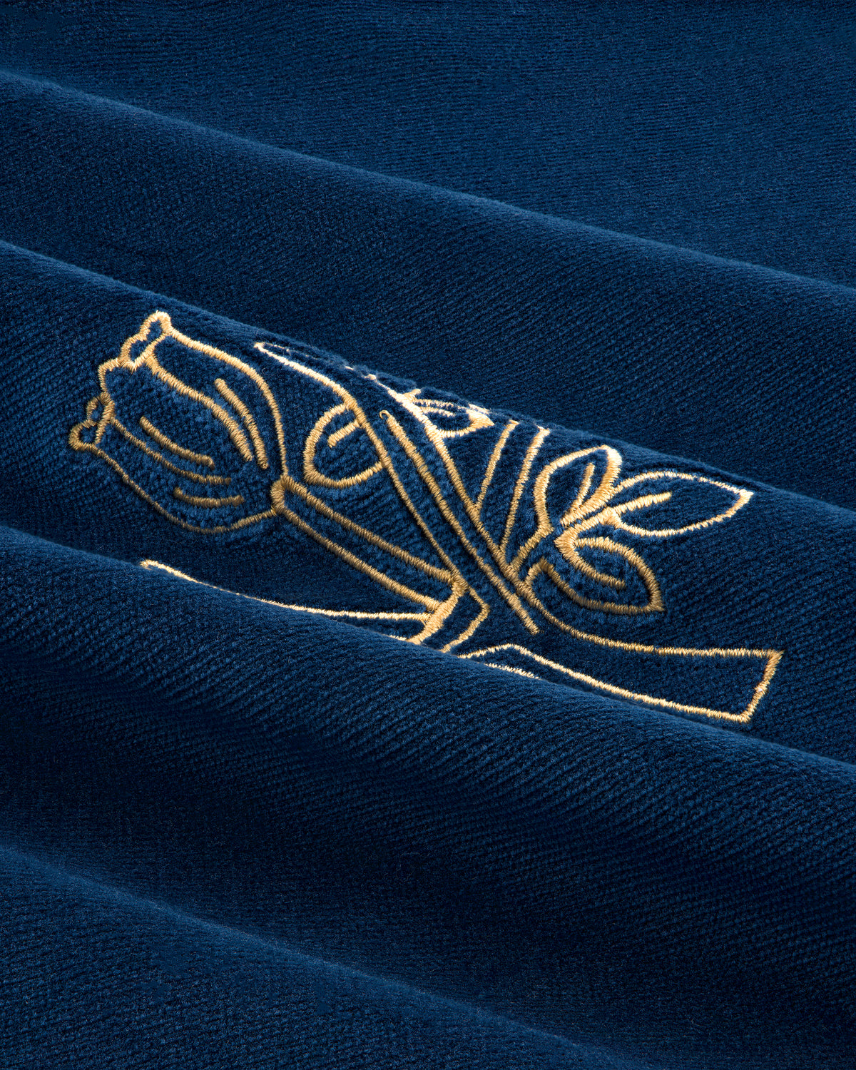 Queens Crest Throw Pillow features navy blue fabric with a gold embroidered rose and leaves.