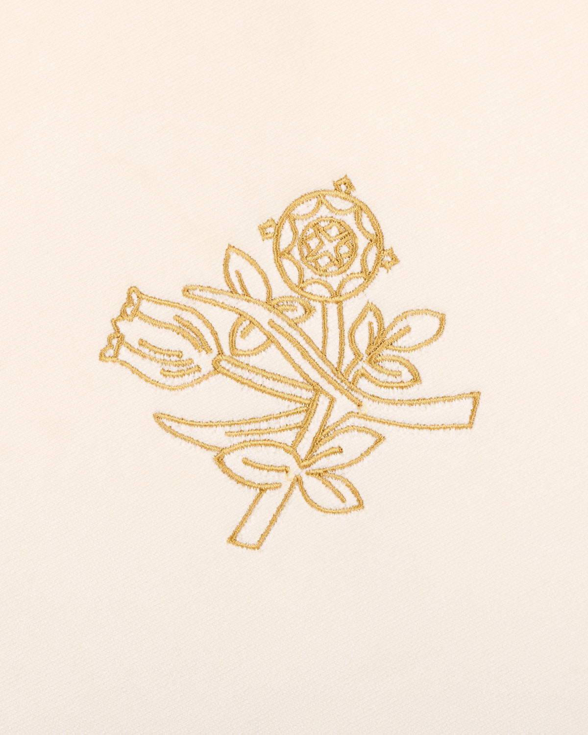 Queens Crest Throw Pillow features gold embroidered roses and buds with leaves on a cream fabric background.
