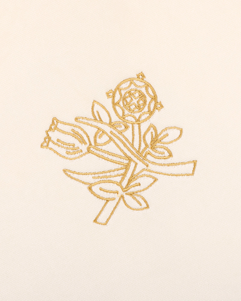 Queens Crest Throw Pillow features gold embroidered roses and buds with leaves on a cream fabric background.