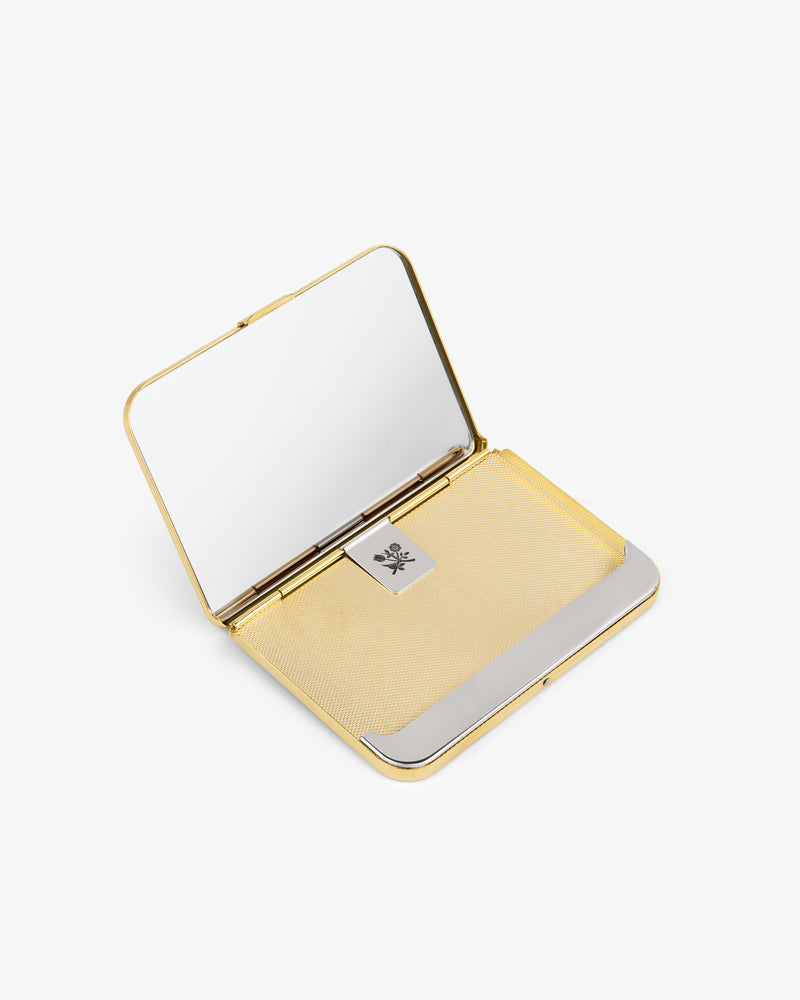 A brass rectangular card case with a mirror and a silver clasp, open on a white background.
