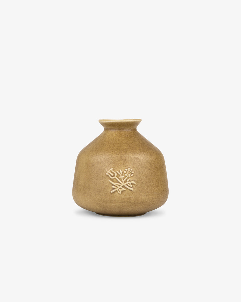 Queens Crest Artisanal Bud Vase: a small tan ceramic vase with a narrow neck and embossed floral design on the front.