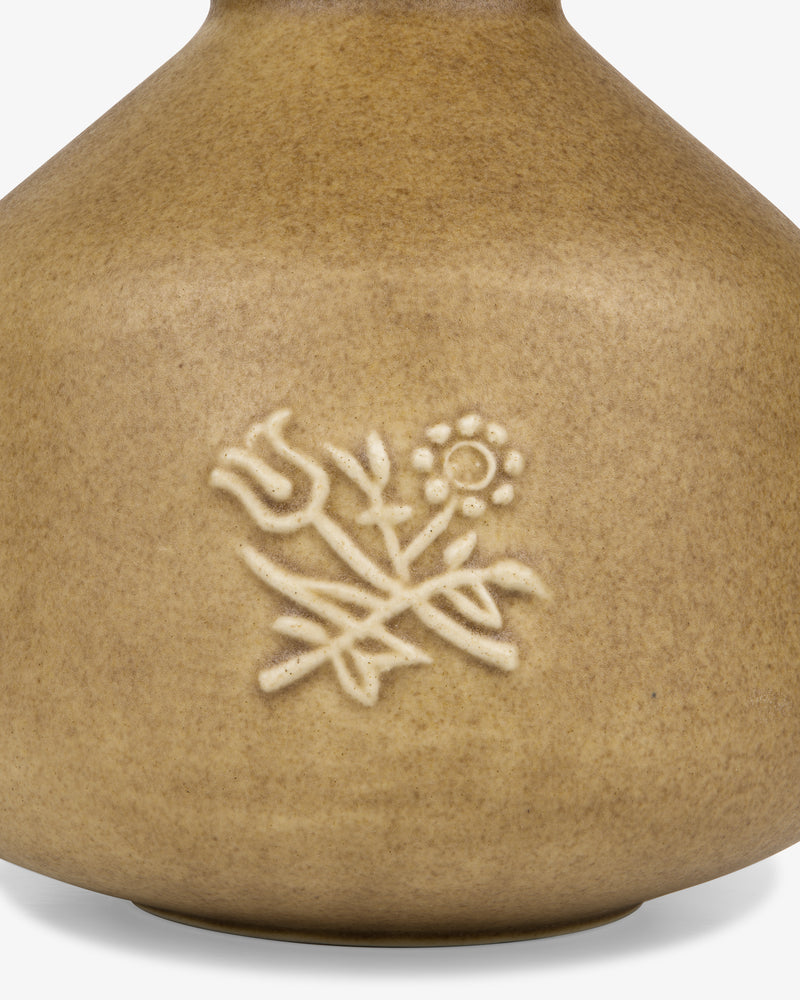 The Queens Crest Artisanal Bud Vase is tan ceramic with raised tulip and daisy floral designs.