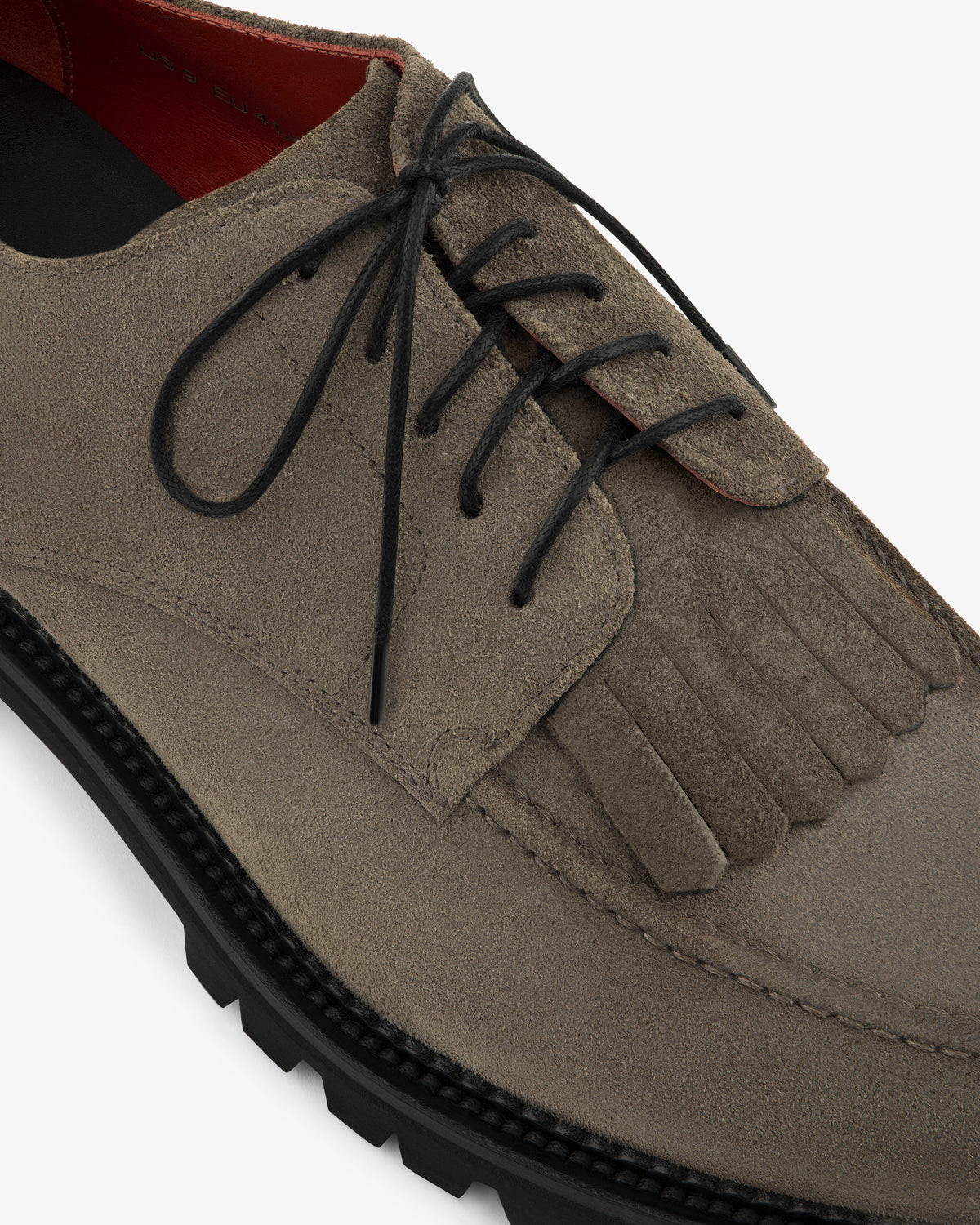 Close-up of the Suede Lug Sole Derby in taupe suede with black laces, fringe detail, and a thick black sole.