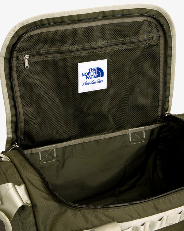 Open olive green ALD / The North Face Base Camp Duffel showing mesh pocket, zipper, and label inside the lid.