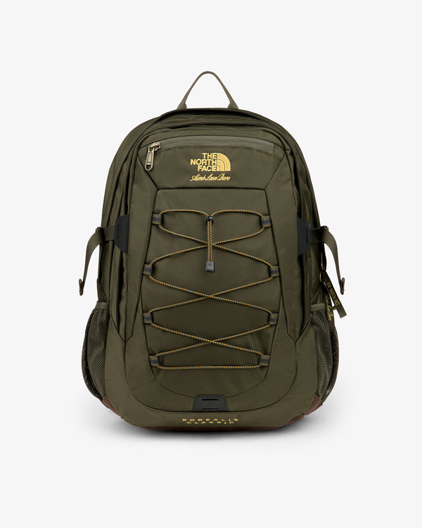 Olive green ALD / The North Face Borealis Backpack with bungee cord, side pockets, and yellow logo on white background.