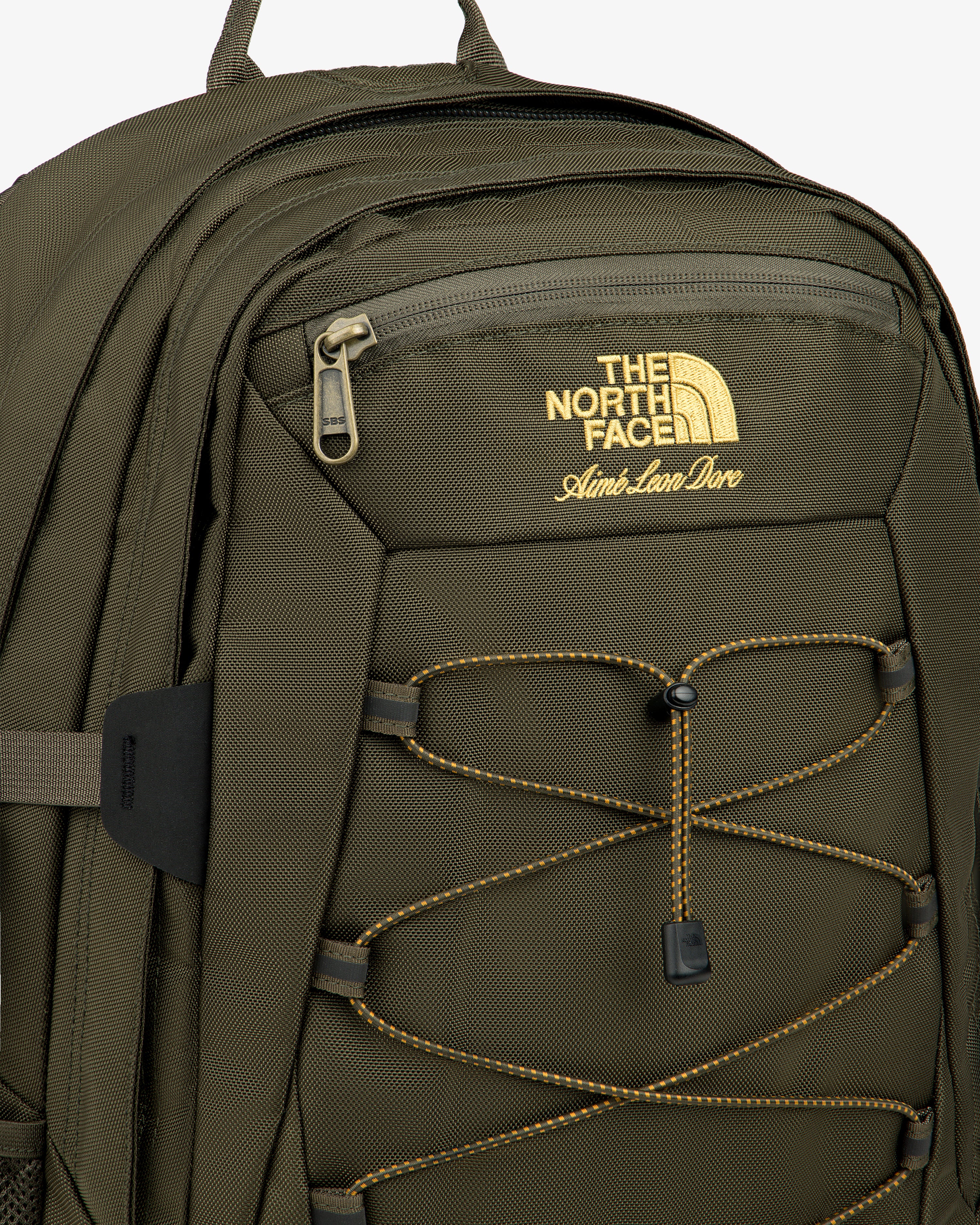 Olive green ALD / The North Face Borealis Backpack with yellow logo, front zip pocket, and yellow bungee cords.
