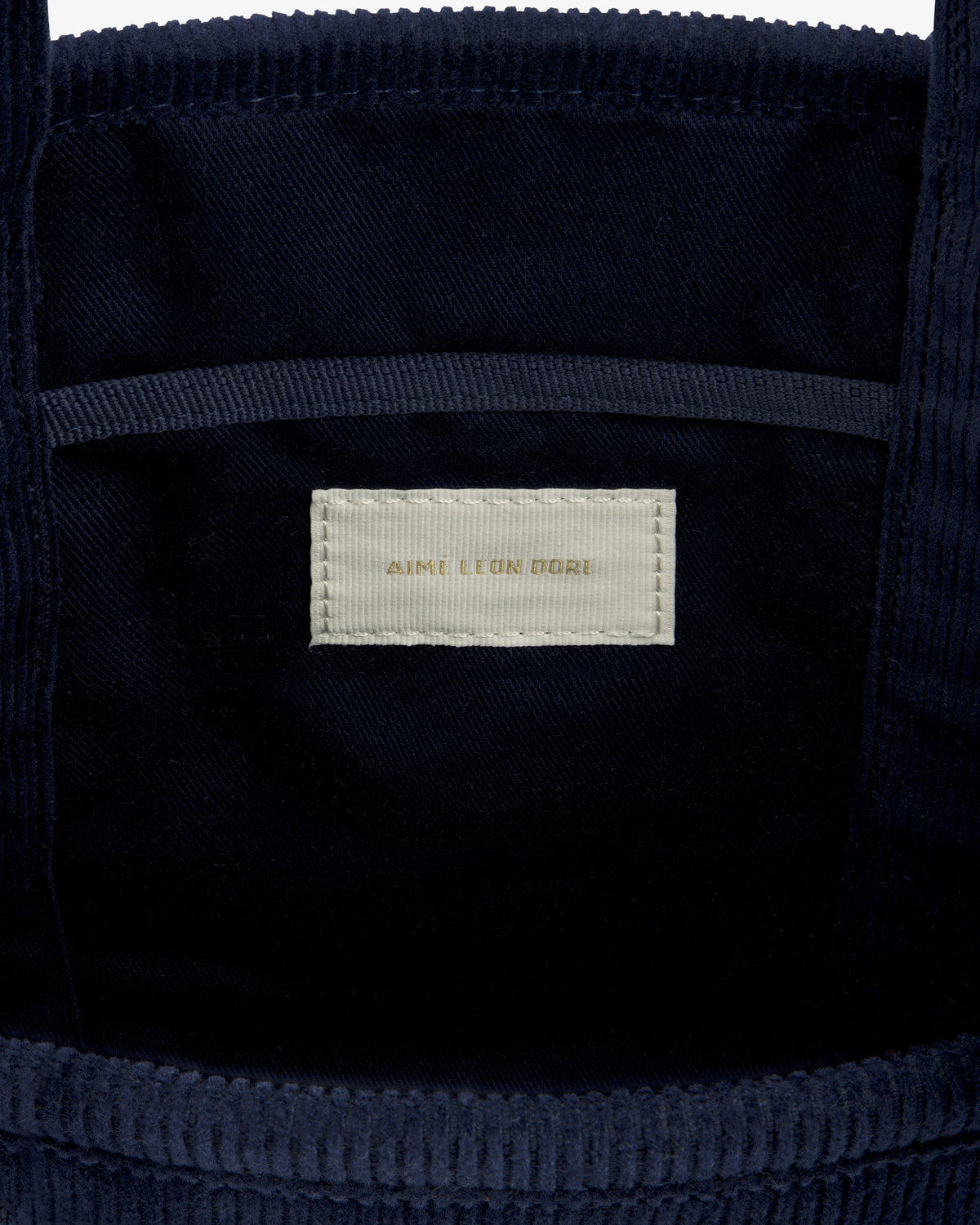 Interior of the Mini Corduroy Unisphere Tote Bag in dark blue corduroy with a cream Aime Leon Dore brand label.
