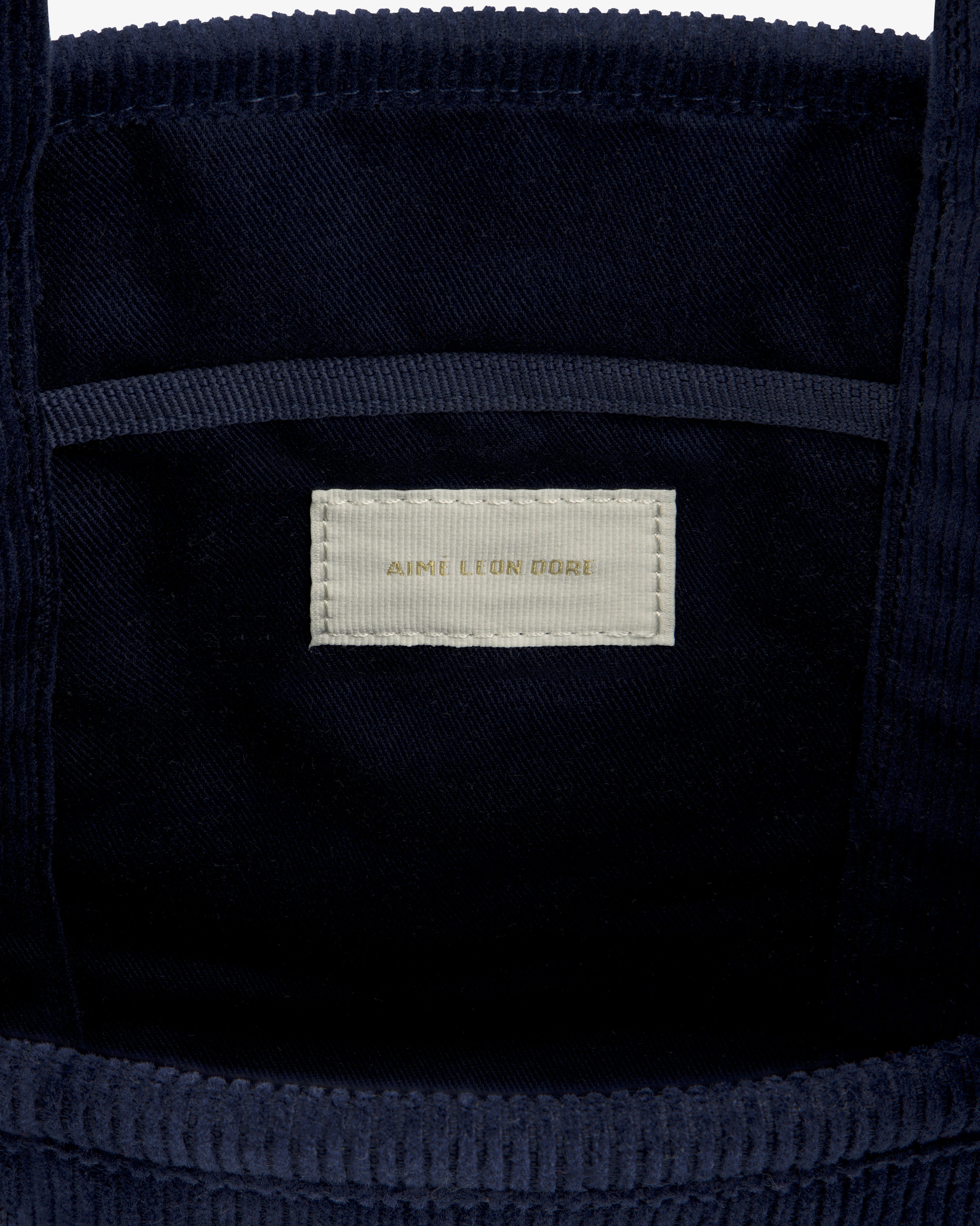 Interior of the Mini Corduroy Unisphere Tote Bag in dark blue corduroy with a cream Aime Leon Dore brand label.