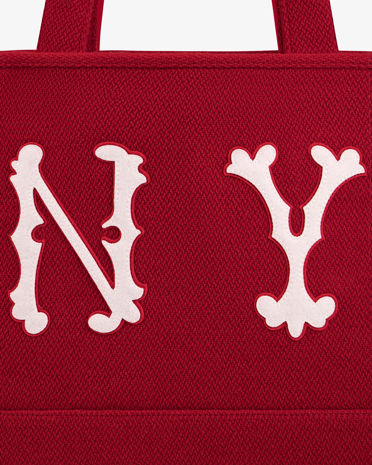 A red, textured NY Highlanders Wool Tote Bag with large, white, decorative N Y lettering appliquéd on the front.