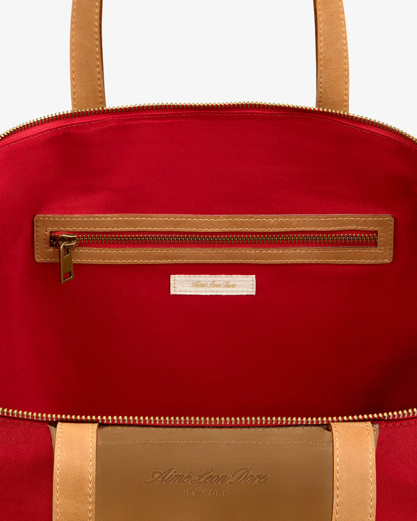 Open Leather Canvas Zip Tote in tan, revealing red lining, zippered pocket, and label stitched below the zipper.