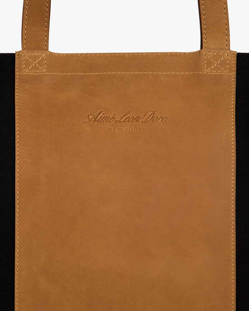 Leather Canvas Zip Tote with Aimé Leon Dore New York embossing and sturdy handles, made of brown leather.